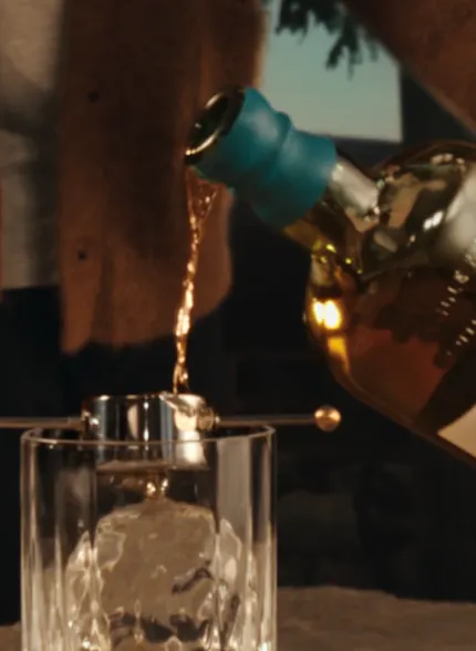 Whisky being poured from a Singleton bottle into a glass with ice