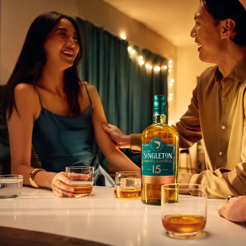 Friends laugh over glasses of whisky and a bottle of The Singleton 15 Year Old 