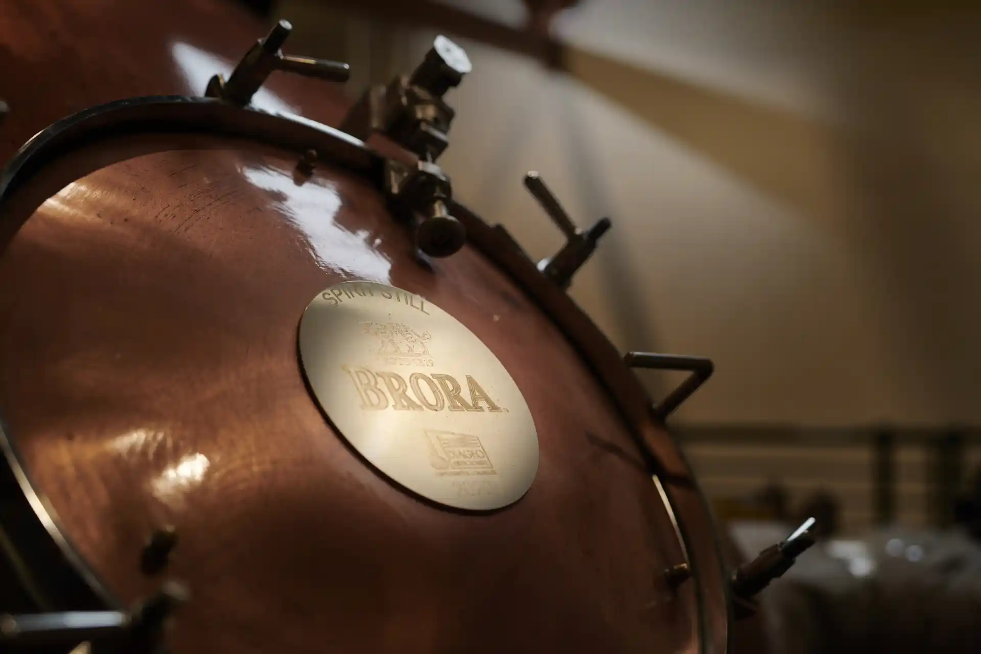 A close-up of a metal whisky still which displays a plaque saying Brora with the distillery’s wildcat logo.