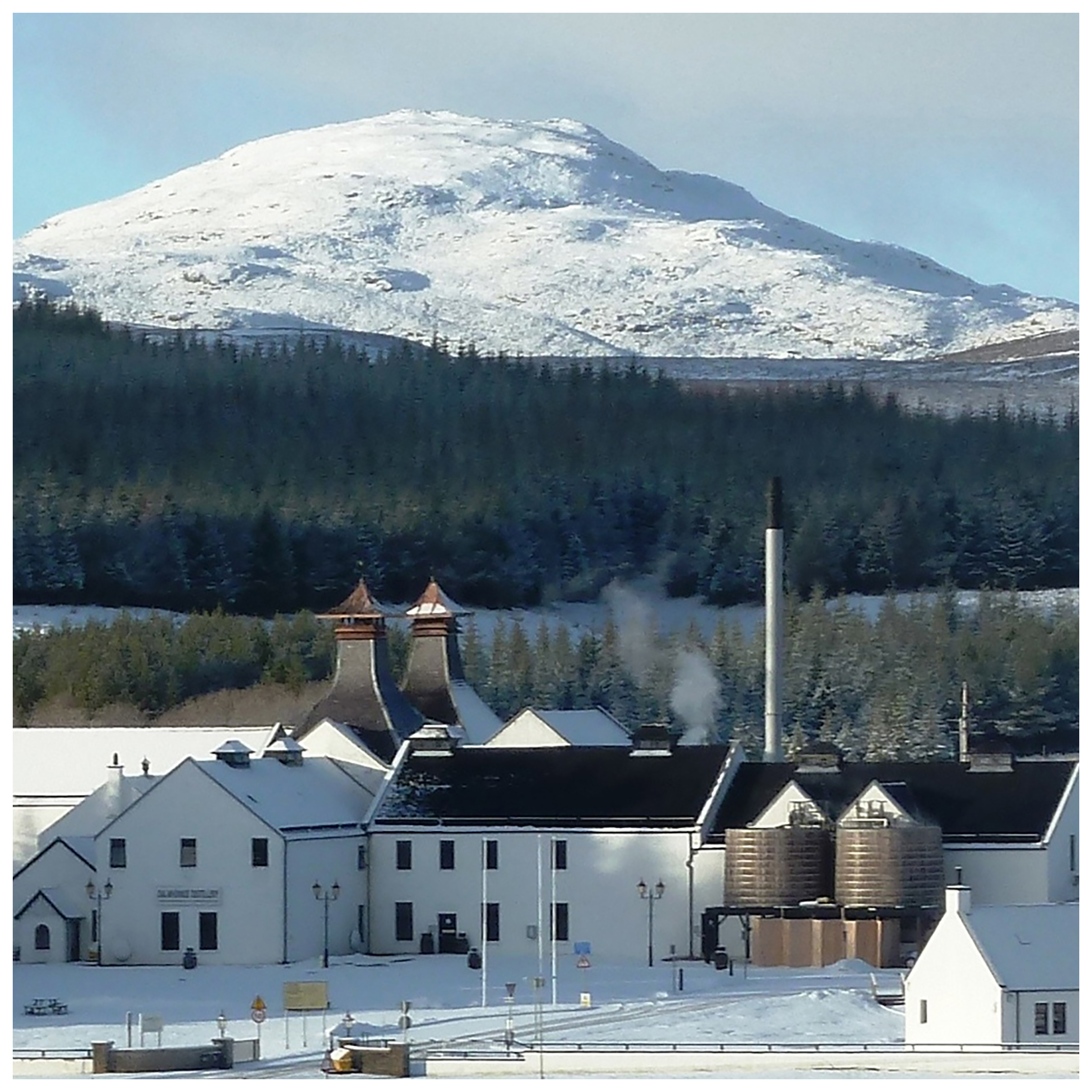 Dalwhinnie distillery sits in front of a large snow covered mountain