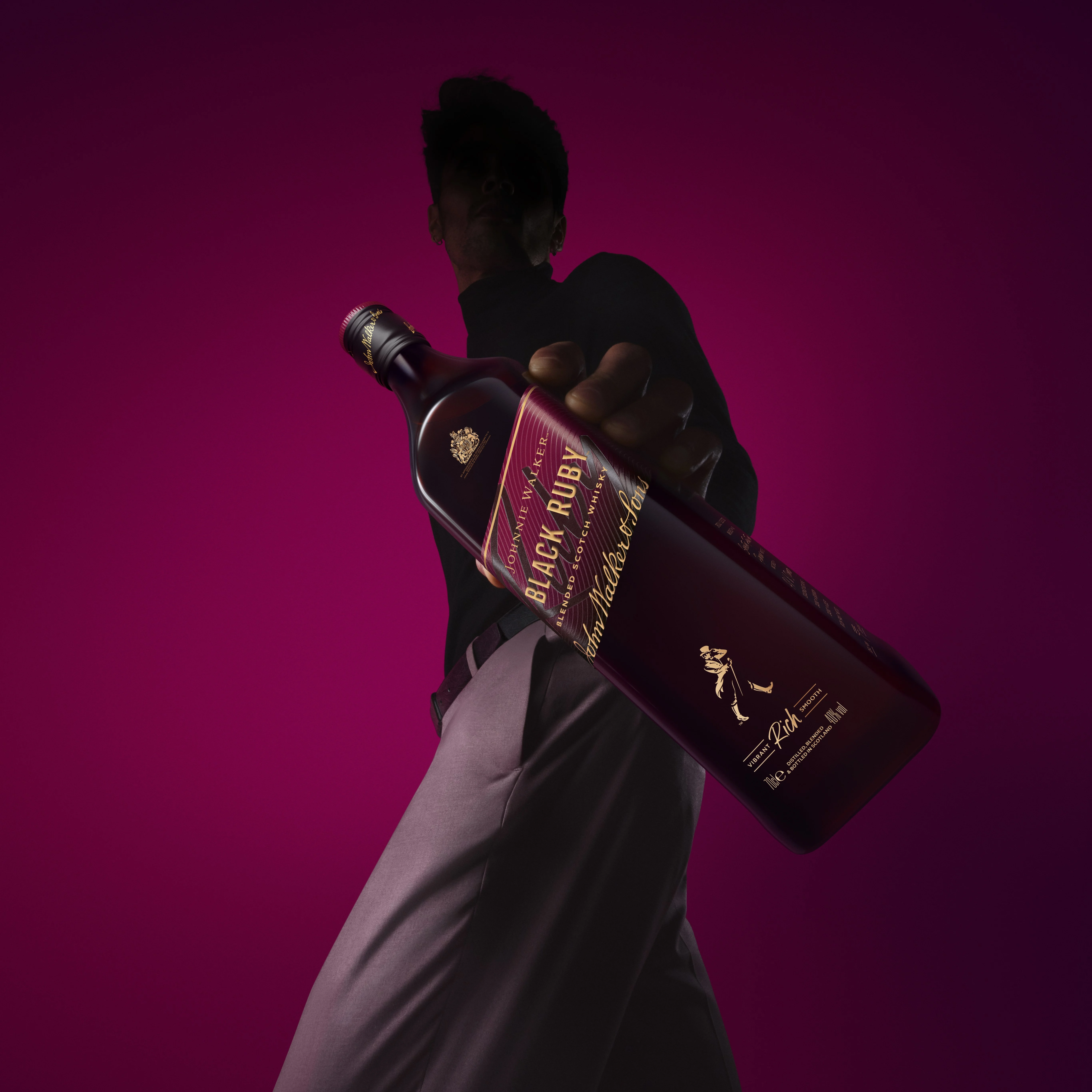 A person holds a bottle of Johnnie Walker Black Ruby Blended Scotch in their hand and shows it off.