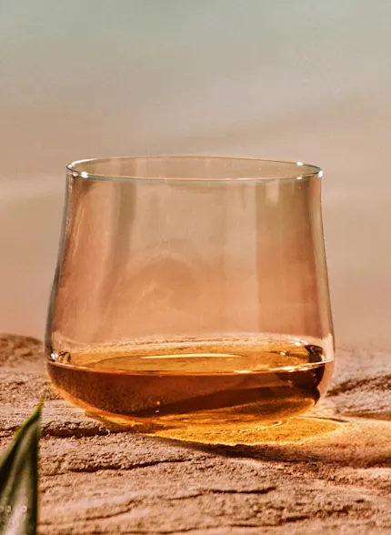 Whisky glass filled with Singleton Glen Ord 17 whisky on a sandy surface