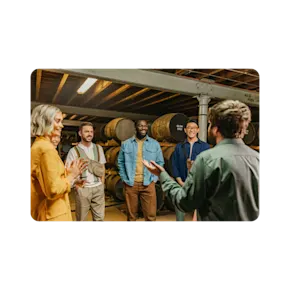 A smiling group surrounded by casks of The Singleton are engaged by a tour guide.