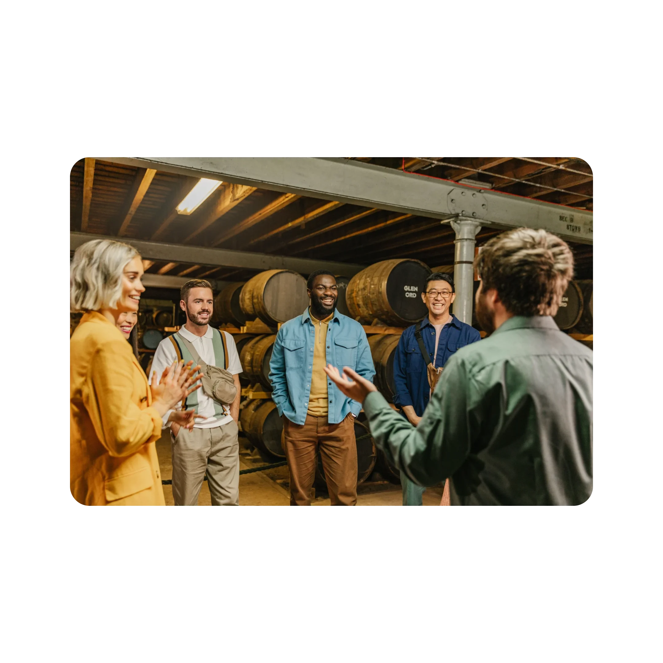 A smiling group surrounded by casks of The Singleton are engaged by a tour guide.