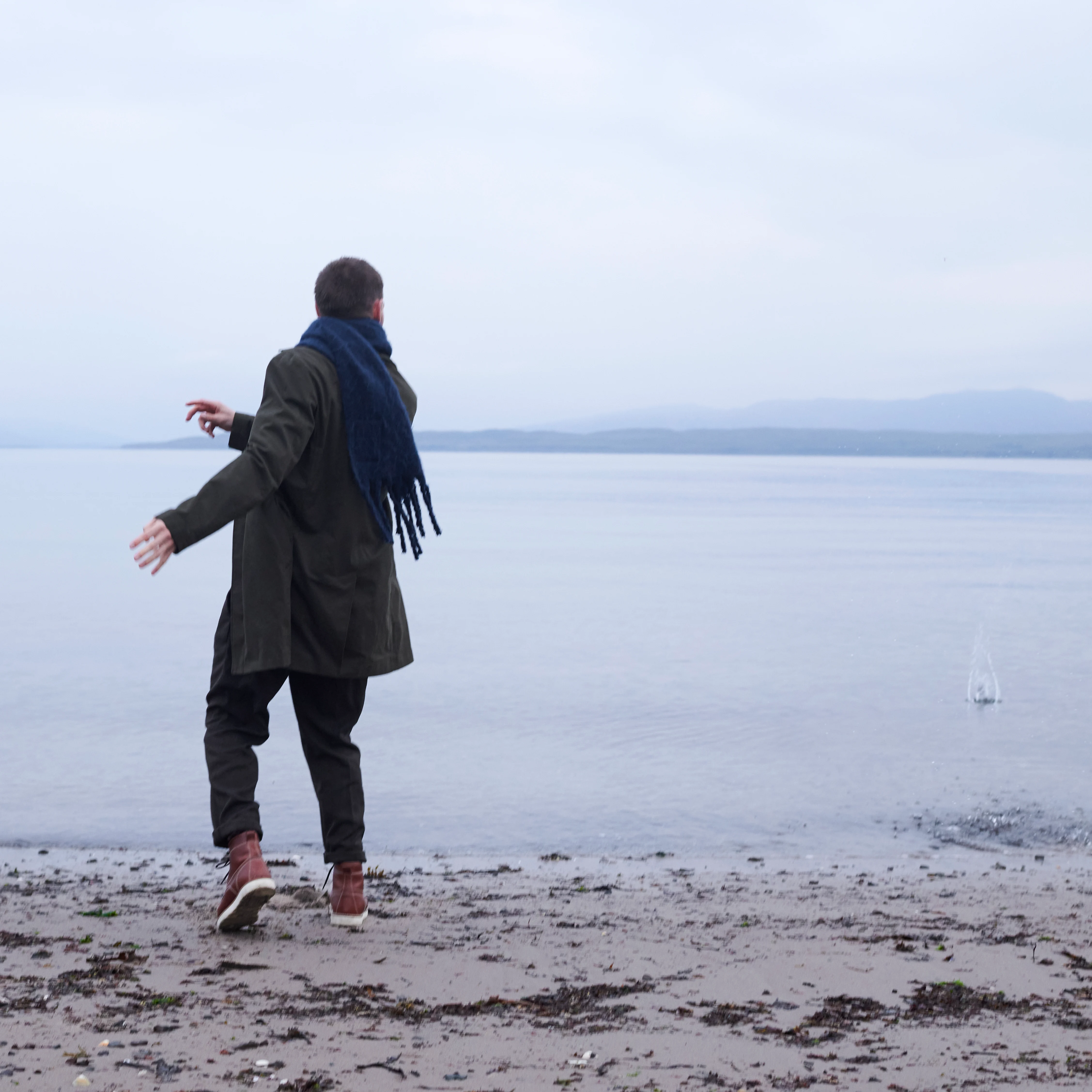 A man skips stones into the sea at Oban Bay