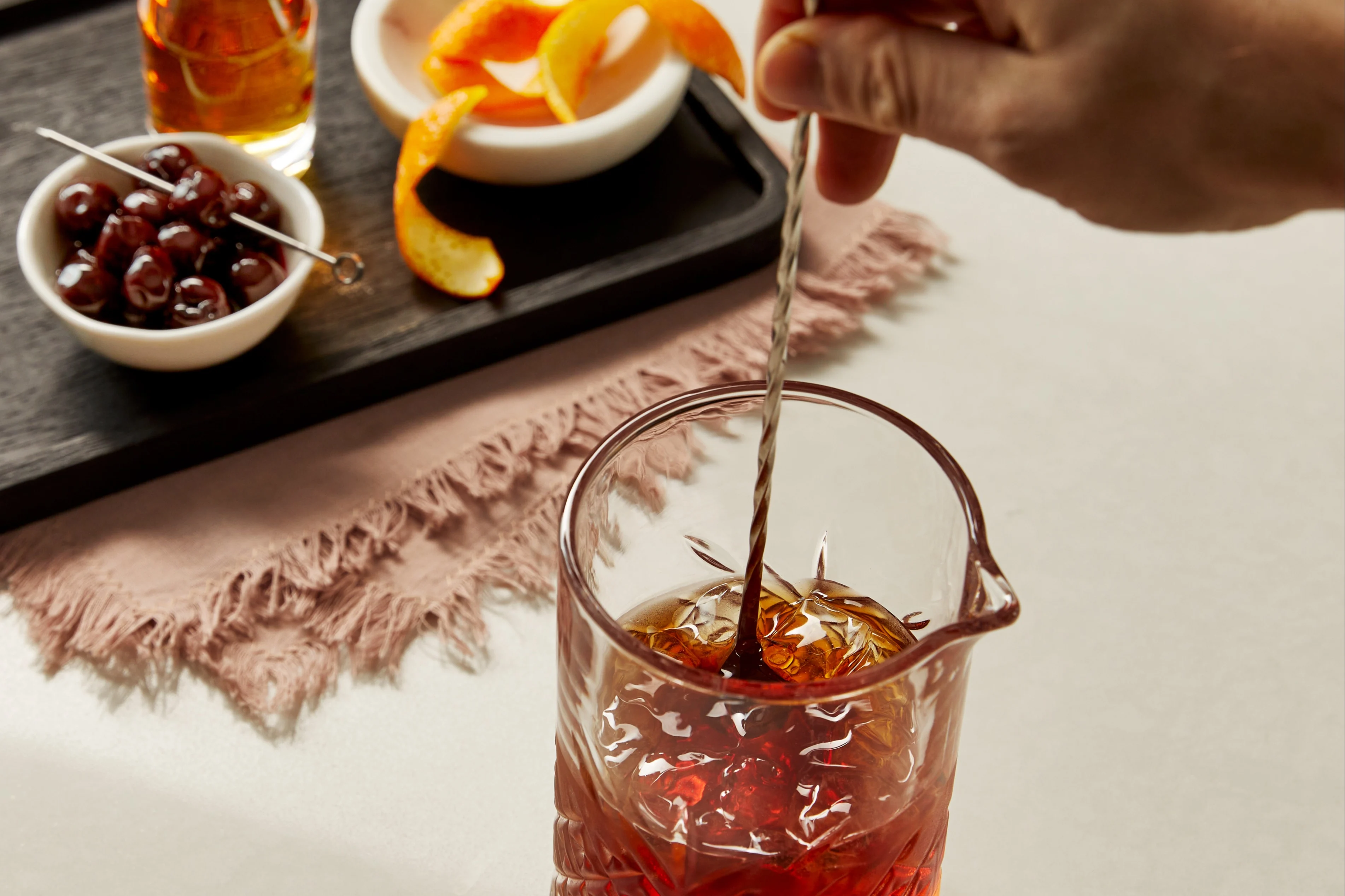 Jemand rührt einen Whisky-Cocktail in einem Rührglas.