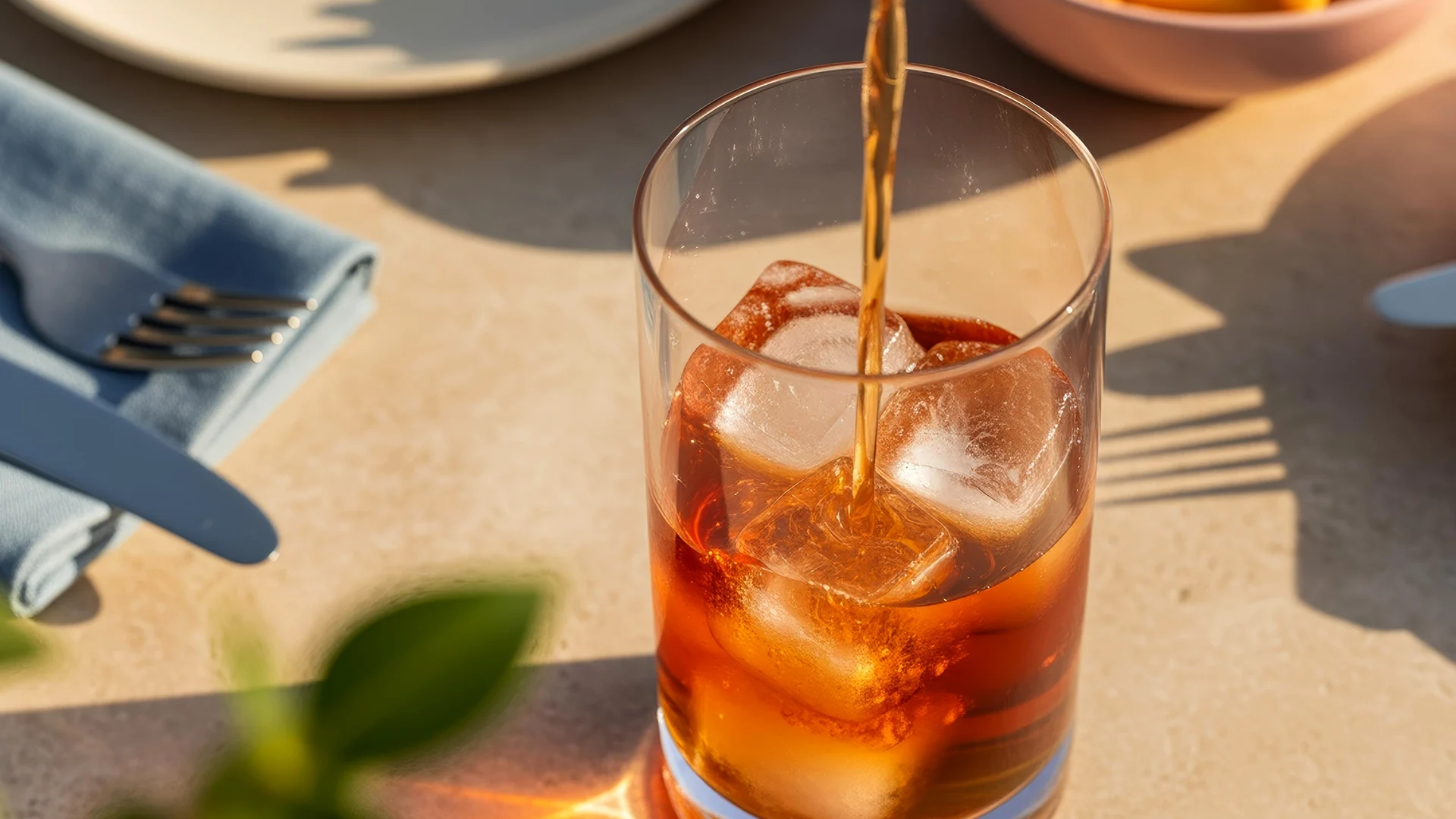Brown liquid is poured into a highball glass