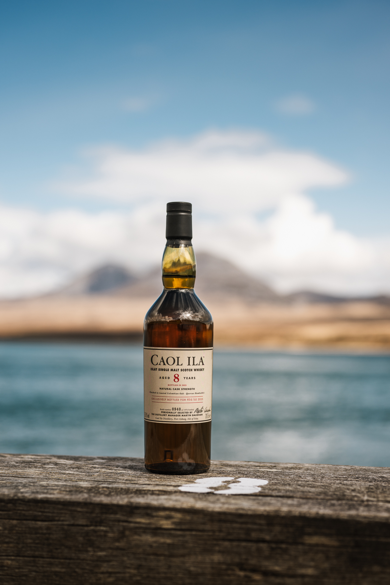 Caol Ila Feis Ile distillery release 8 year old sat in front of a body of water in Islay.