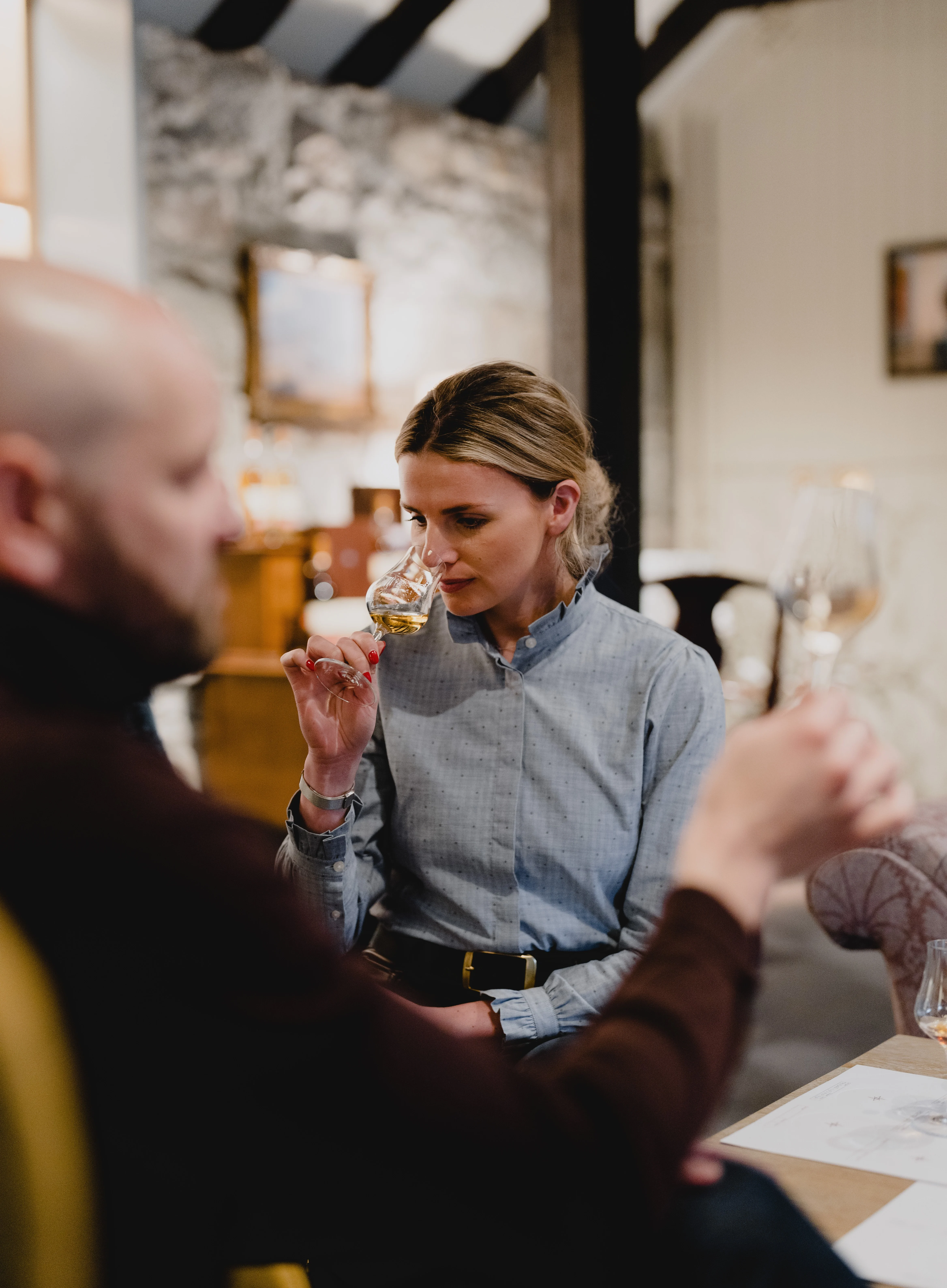 A woman smells a glass of whisky at a tasting.