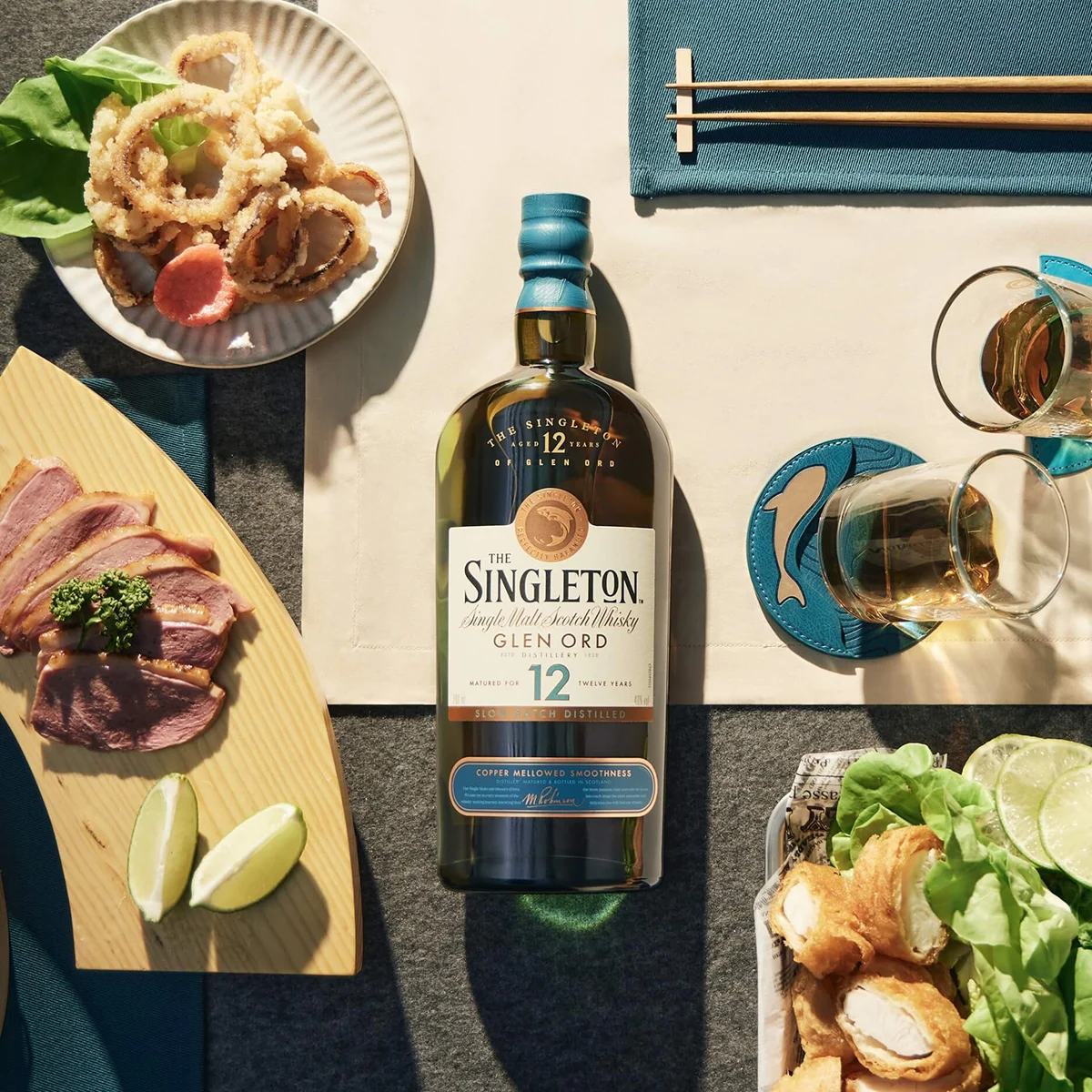 The Singleton Of Glen Ord 12 Year Old Single Malt Scotch Whisky bottle on a table alongside a spread of platters