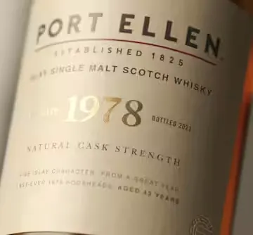 A bottle of Port Ellen whisky lies label-up on a neutral backdrop.