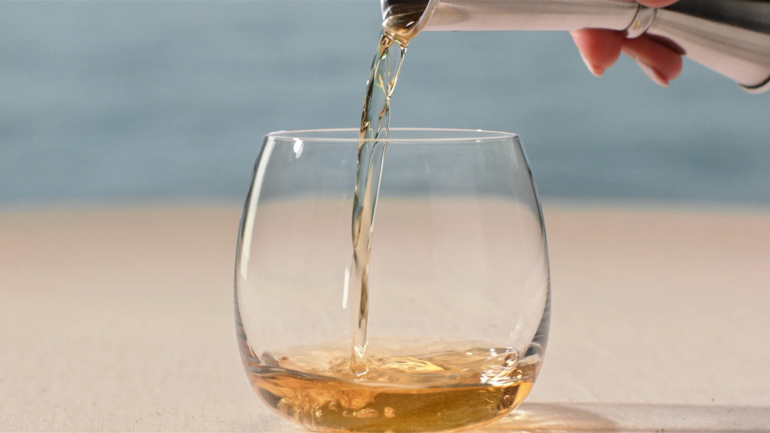 Oban whisky wordt in een rond glas geschonken met de zee op de achtergrond