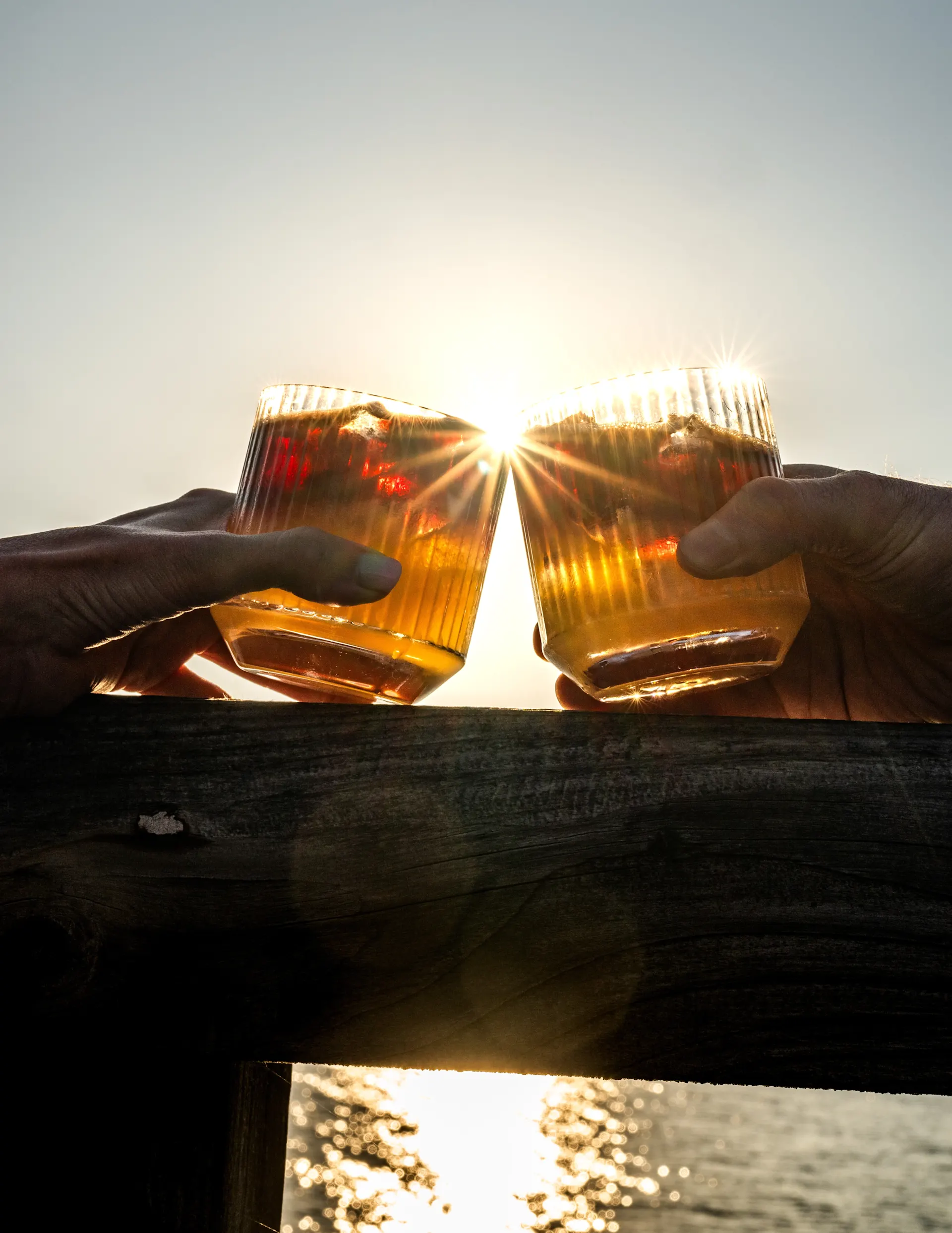 Twee vrienden proosten met whiskyglazen met uitzicht op Lagavulin Bay