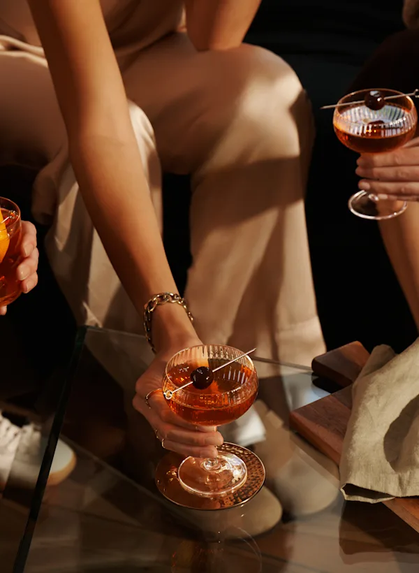 Three women sit on a sofa holding assorted whisky cocktails