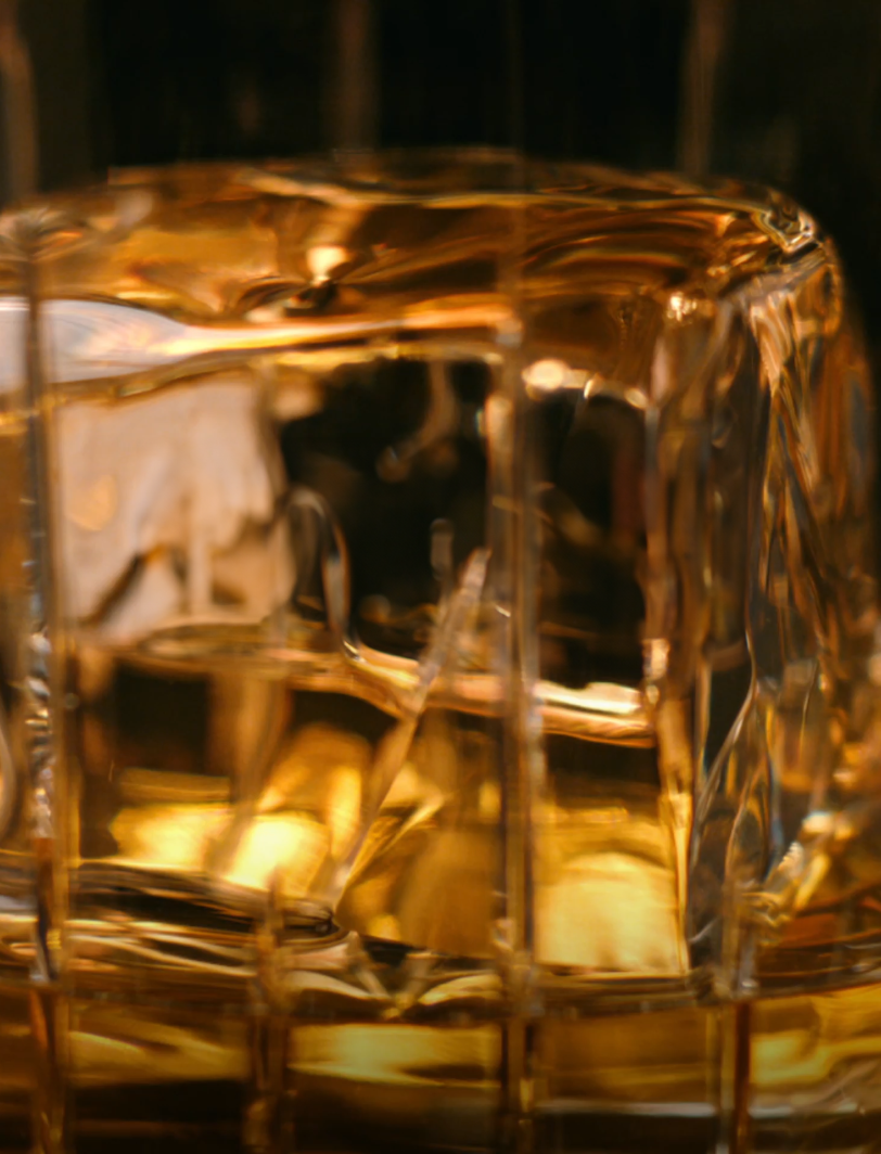 Close-up of a glass of whiskey with a large ice cube showcasing golden hues