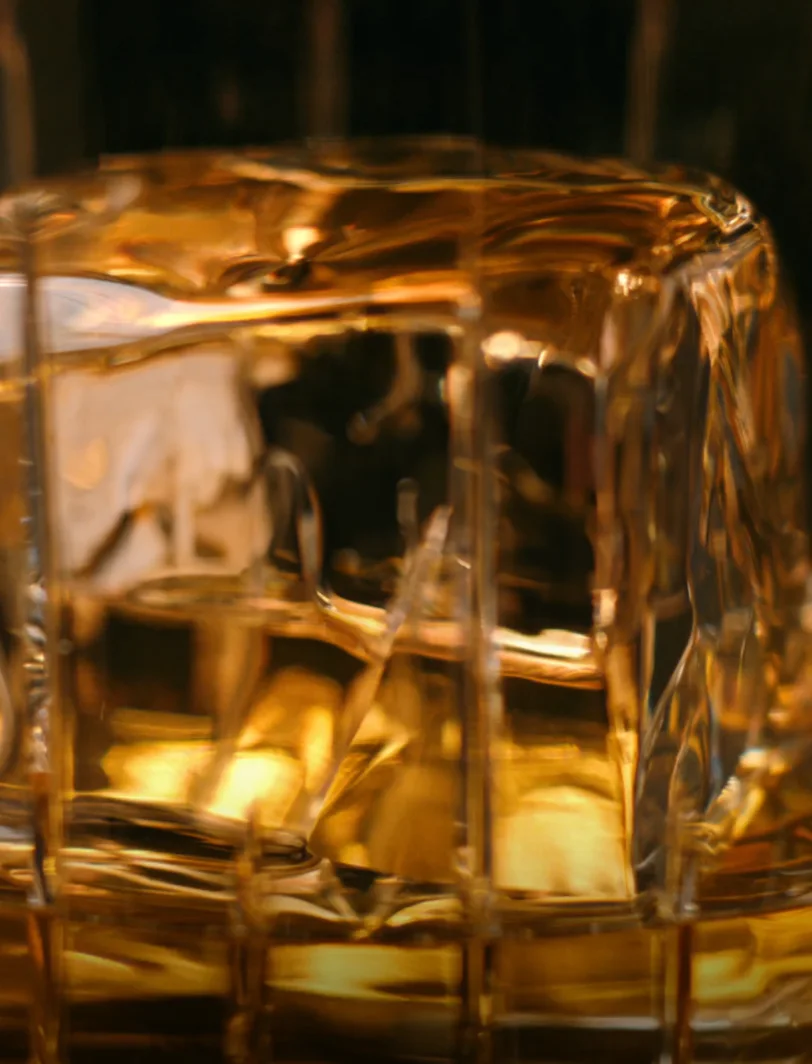 Close-up of a glass of whiskey with a large ice cube showcasing golden hues