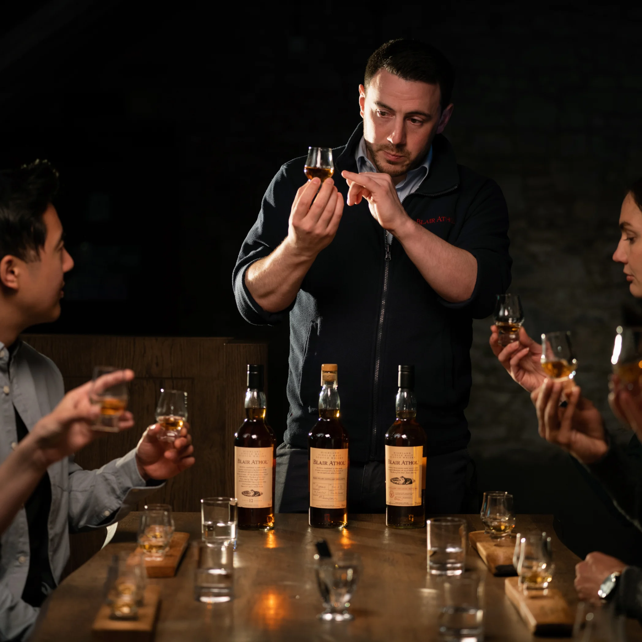 Tutored whisky tasting experience where tour guide is holding a whisky dram while showing visitors the colour and aspect of the whisky. 