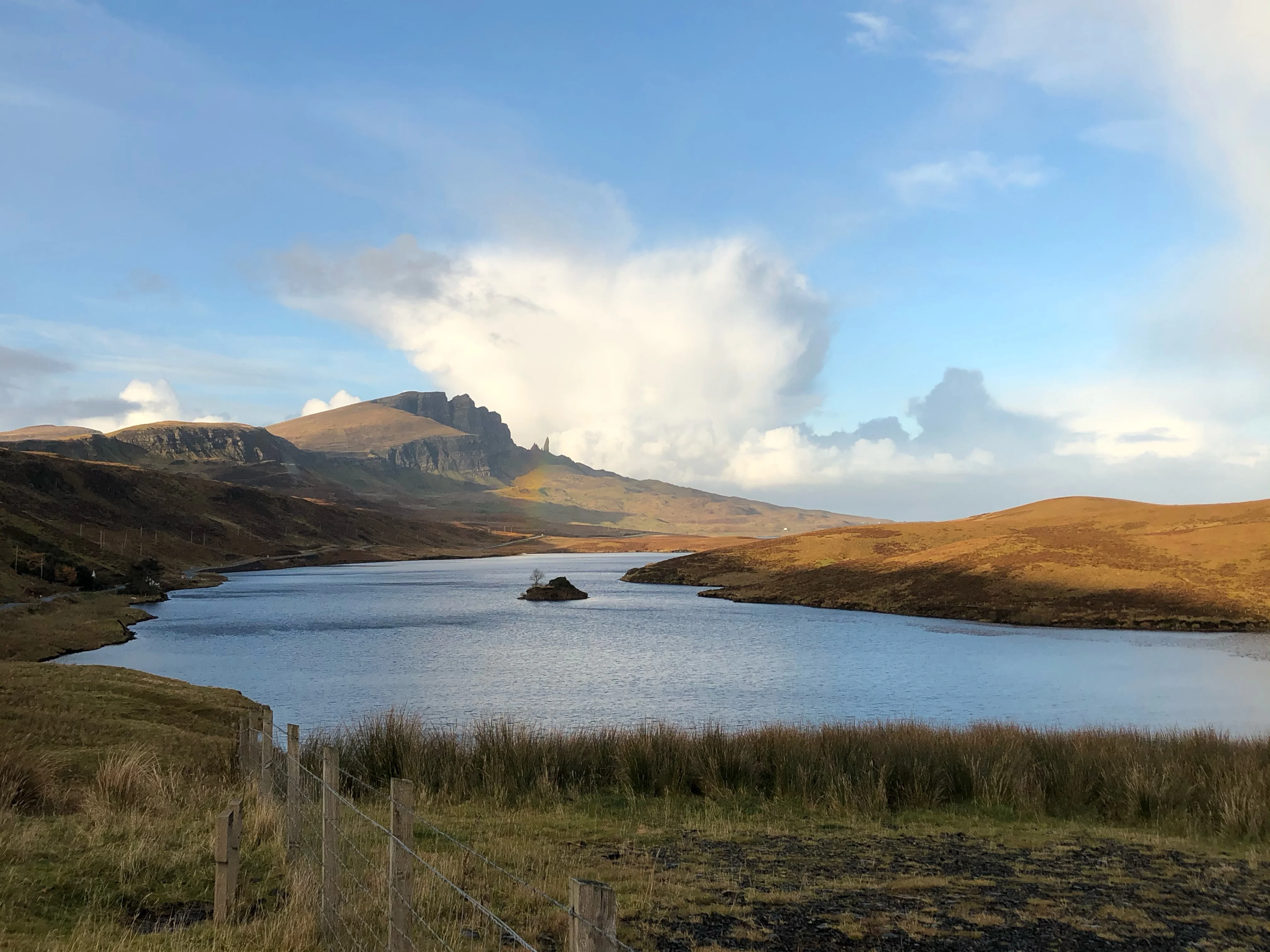 A Scottish loch is pictured from a distance, showing the surrounding mountainous landscape. 