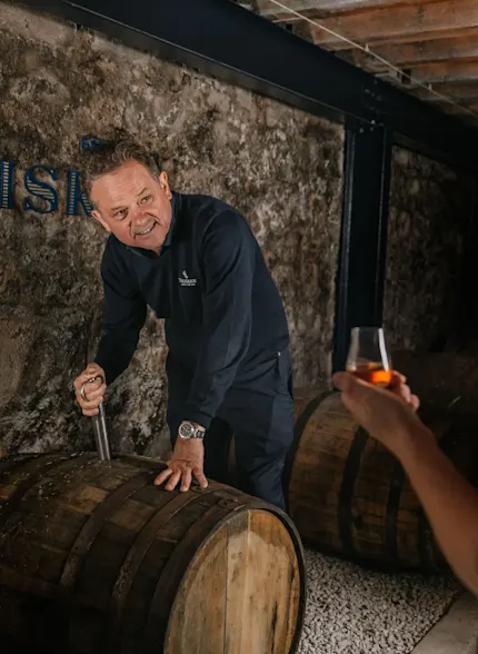 A Talisker employee shows a guest a whisky cask on a distillery tour