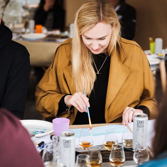 A woman painting during an art class with whisky tasting at Fèis Ìle