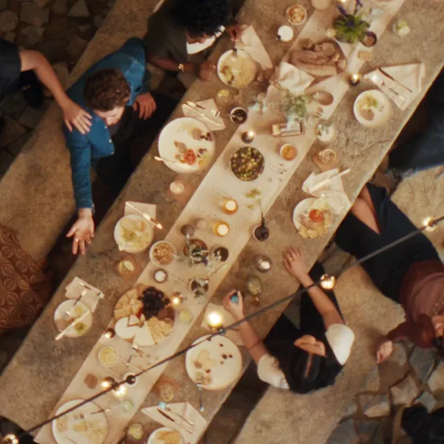 Bovenaanzicht van een rustieke eettafel buiten met mensen die genieten van eten en drinken