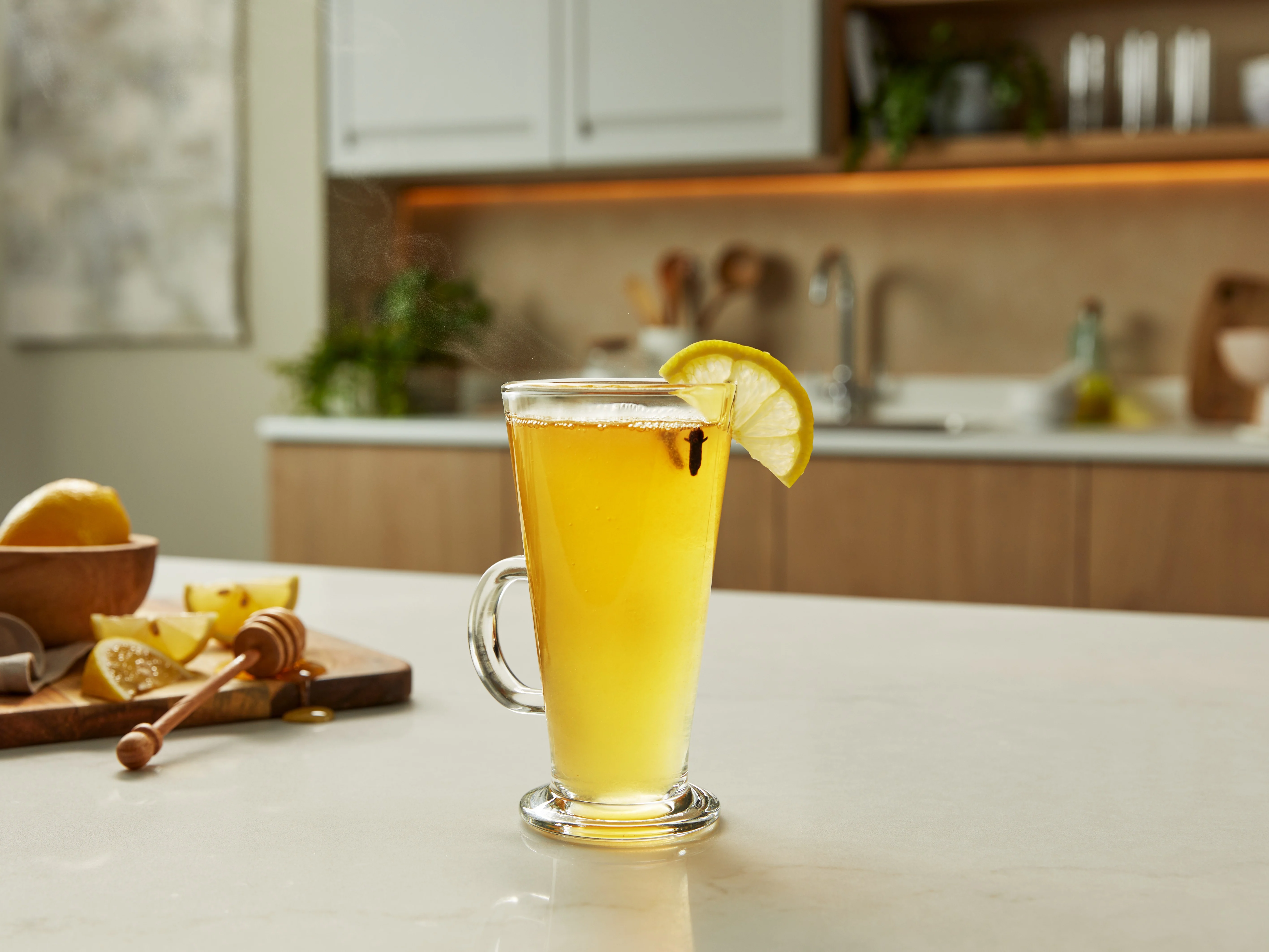 Ein Hot Toddy in einem hitzebeständigen Latte-Glas mit einer Zitronenscheibe als Garnitur