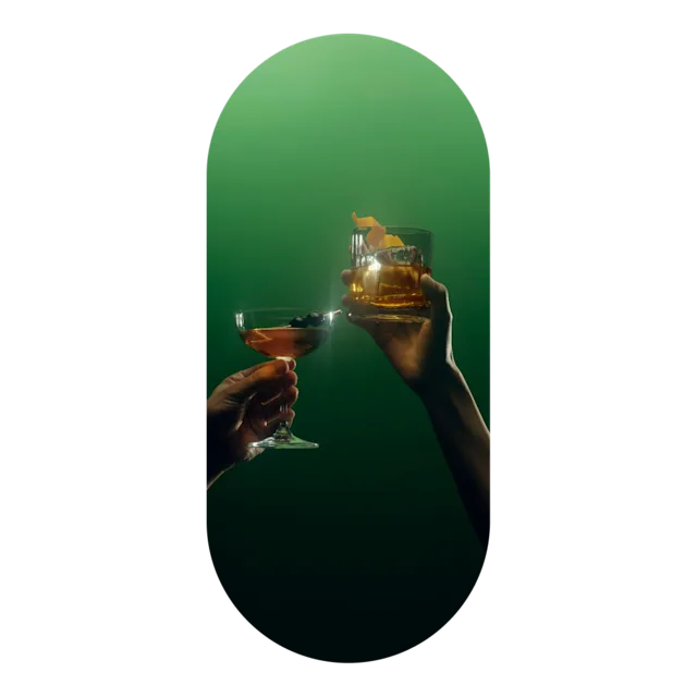 Twee handen met Lagavulin cocktails proosten op elkaar in groen getint licht