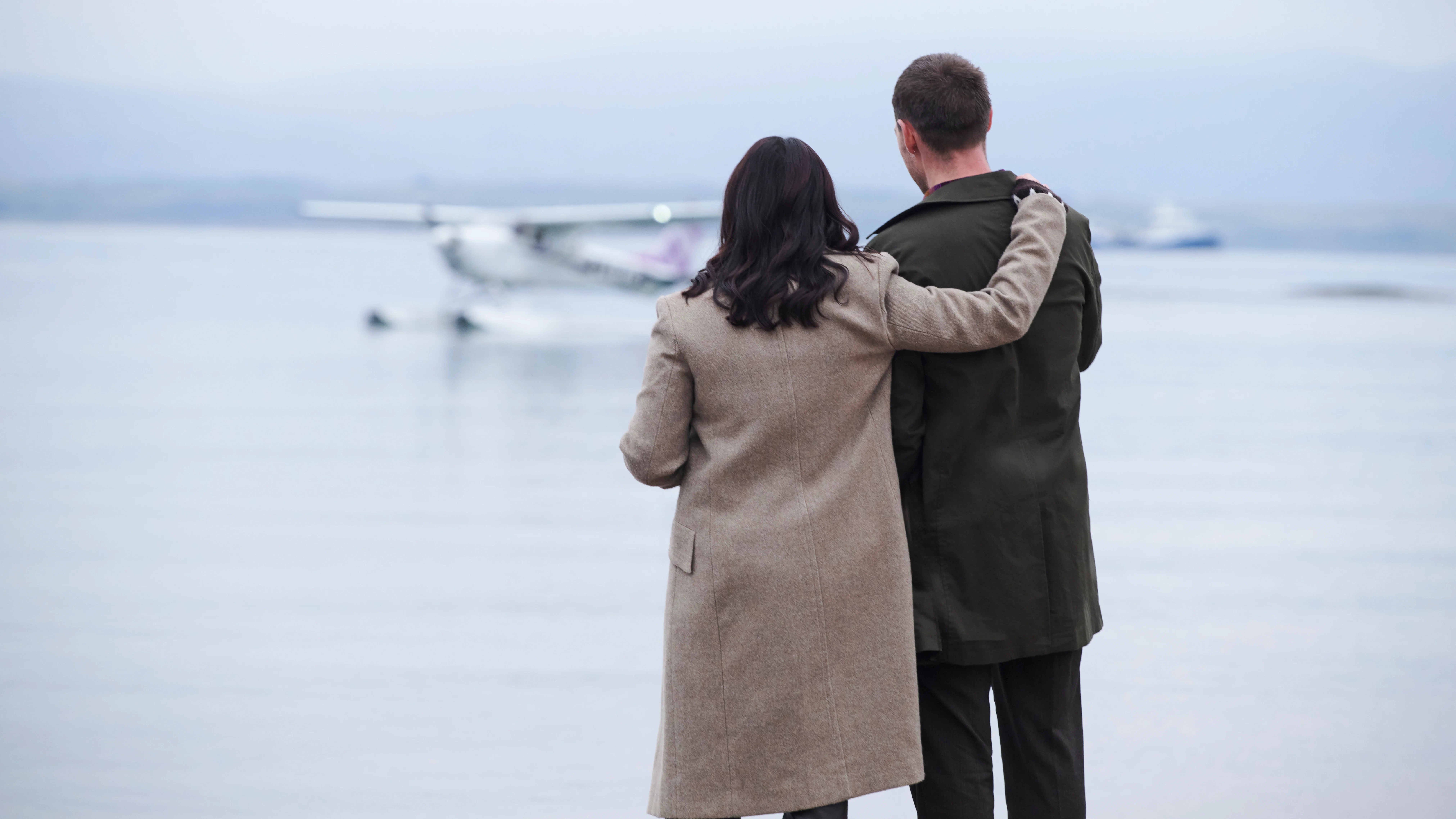 A woman places her arm around a man as they look out on Oban Bay