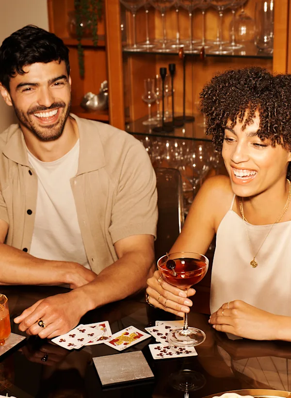 Ein Mann und eine Frau sitzen an einem Tisch mit Spielkarten und Whisky-Cocktails