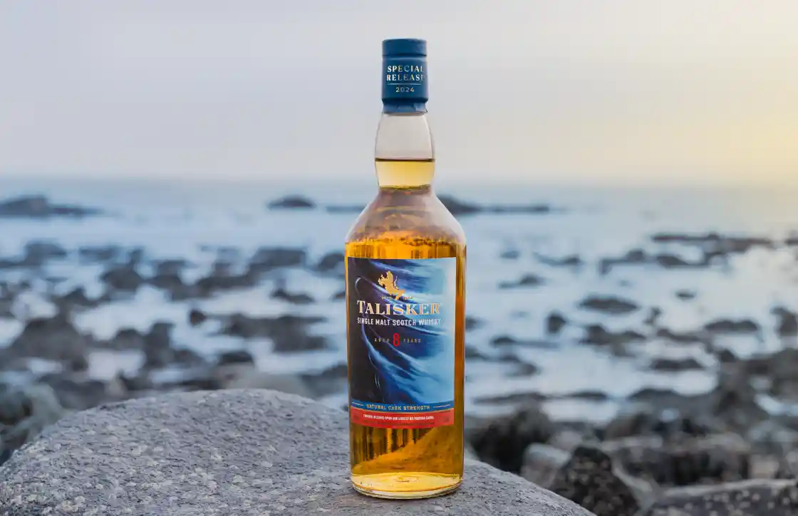 Talisker Tidal Churn Single Malt Whisky 70cl fles zittend op een rots met een achtergrond van een stille zee