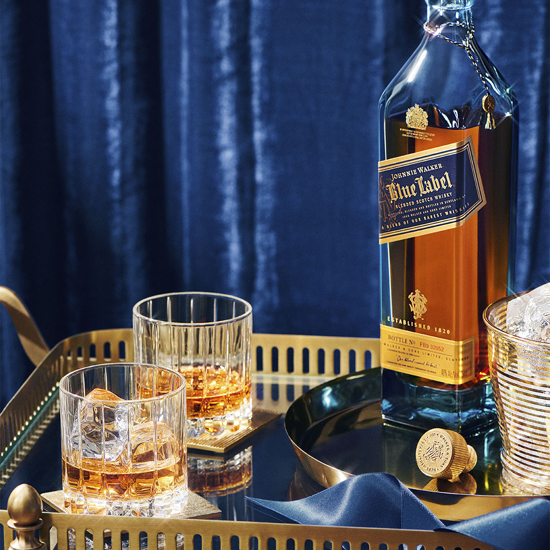 Eine Flasche Johnnie Walker Blue Label auf einem Tablett mit zwei Whiskygläsern 