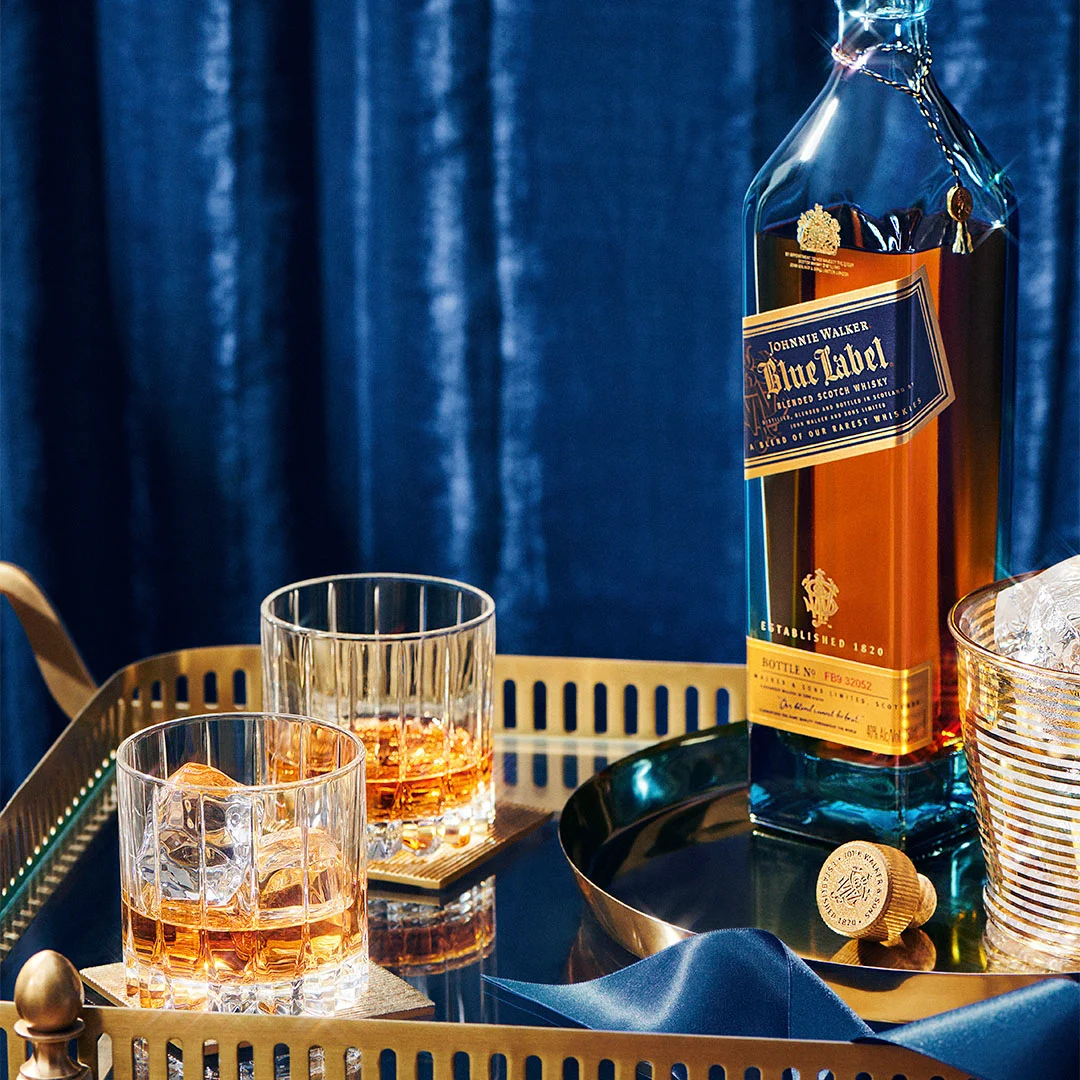 A bottle of Johnnie Walker Blue Label on a tray with two whisky glasses 
