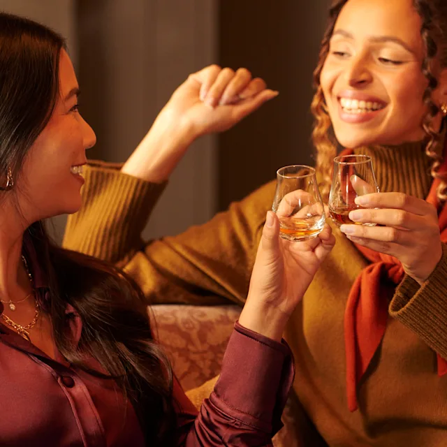 Two women drinking from whisky tasting glasses