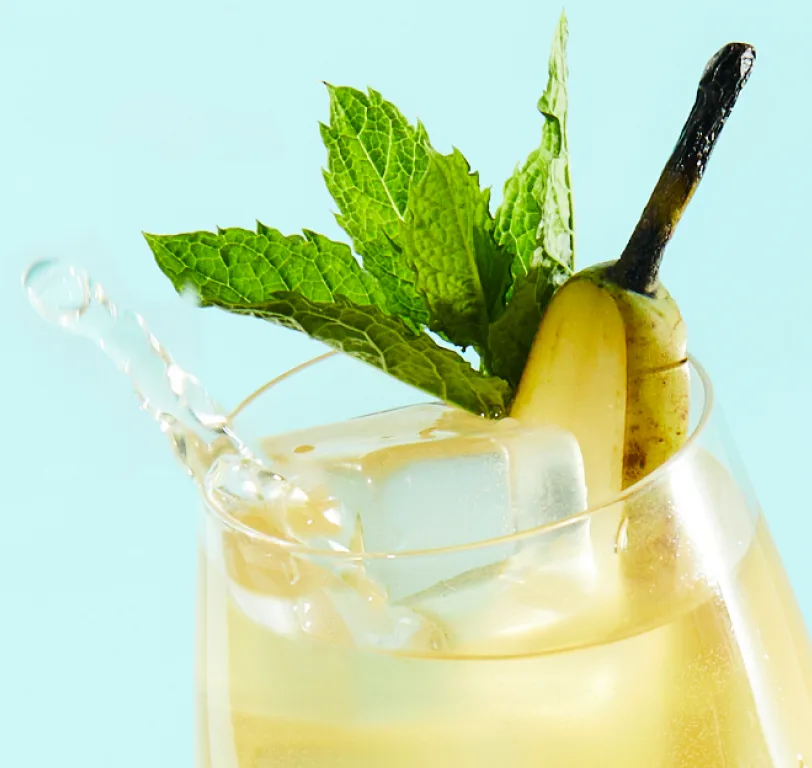 A highball whisky cocktail with a pear and mint garnish.