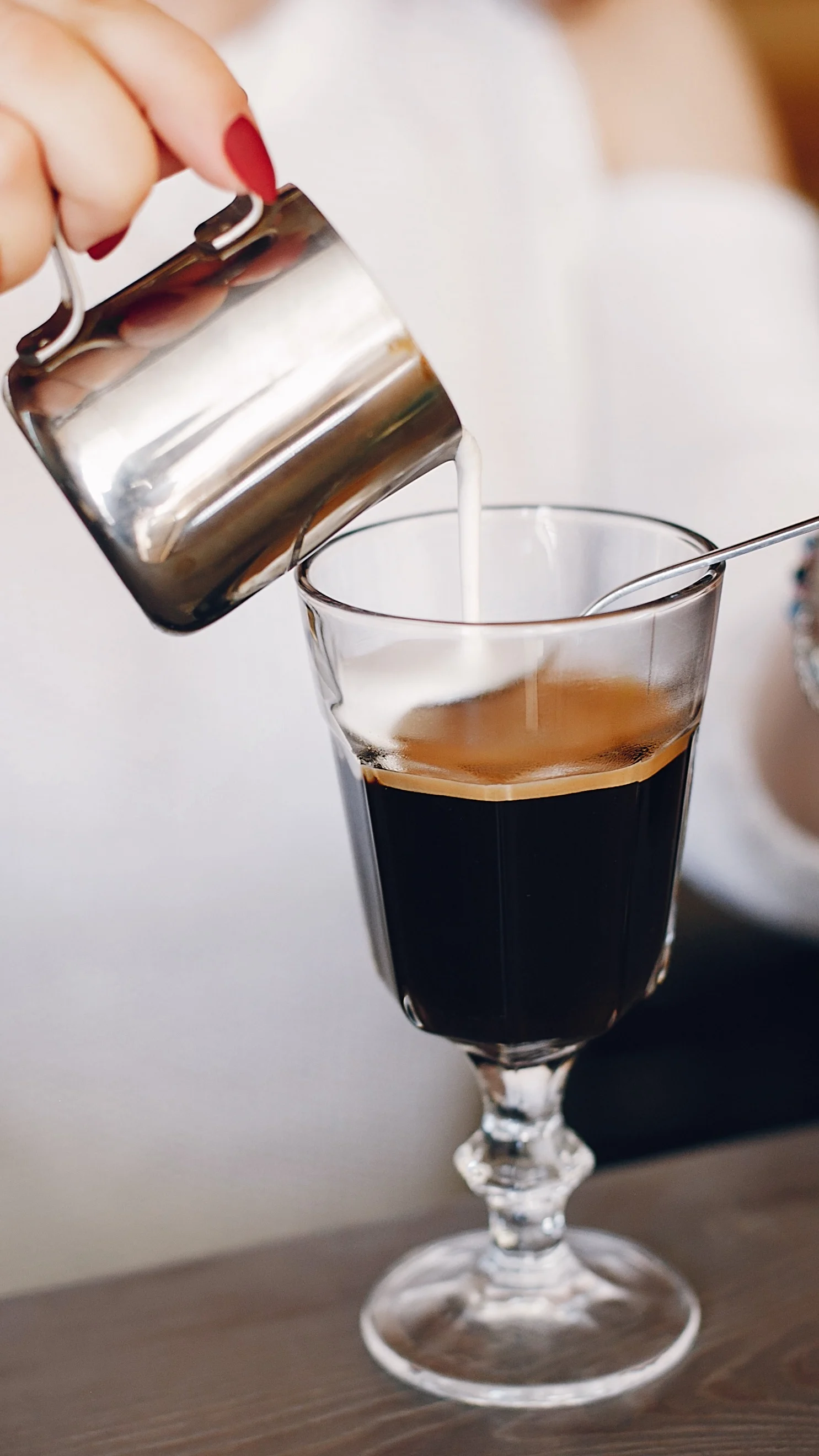 Eine Person gießt Sahne auf einen Irish-Coffee-Cocktail