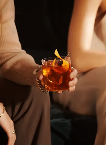 A woman holds an Old Fashioned cocktail