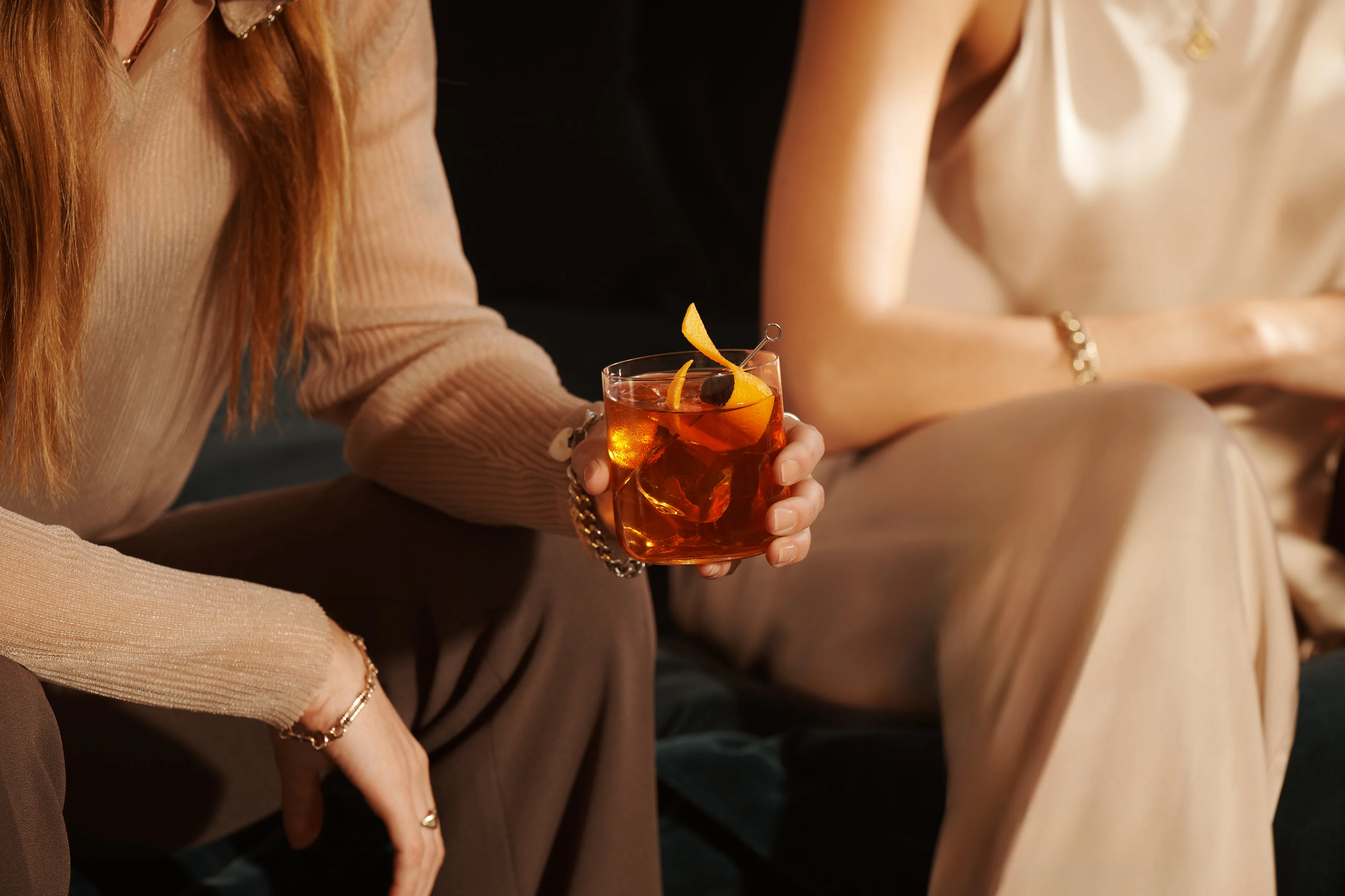 A woman holds an Old Fashioned cocktail