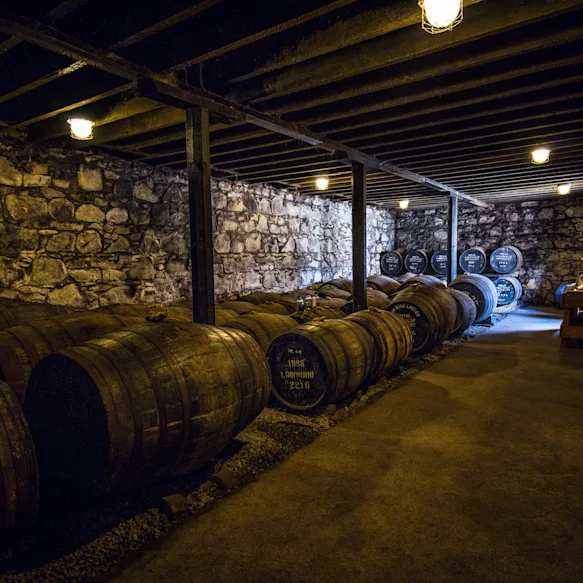 Barrels of Royal Lochnagar's finest whisky age in a dimly lit room.
