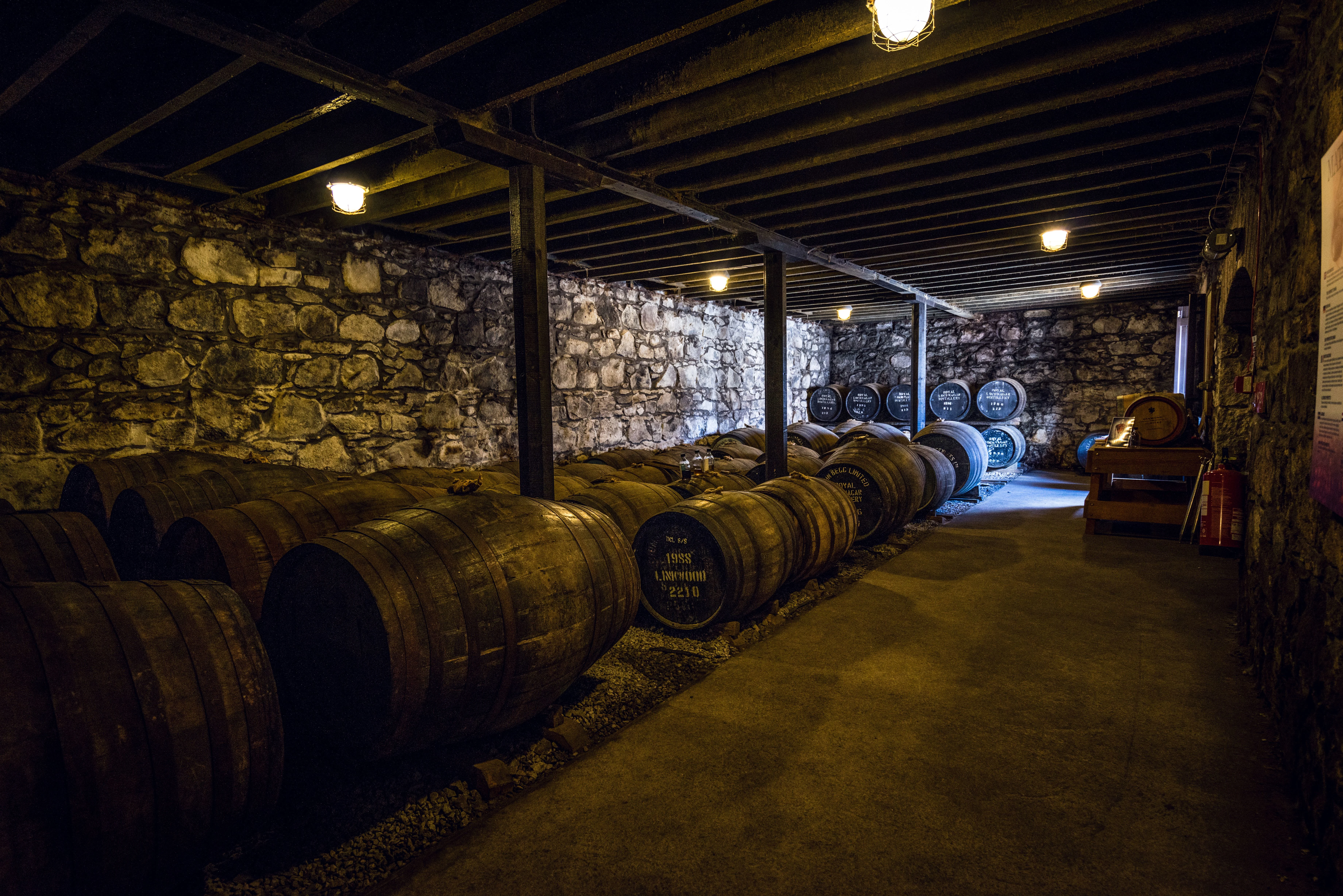 Barrels of Royal Lochnagar's finest whisky age in a dimly lit room.