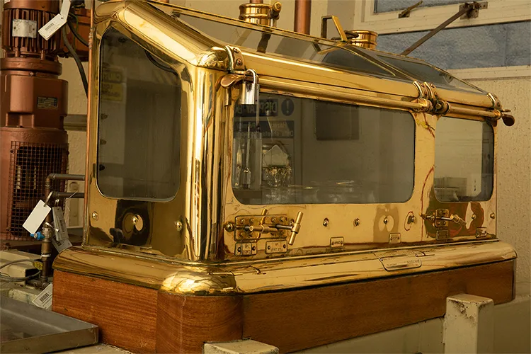 Eine glänzende Destilliermaschine aus bronziertem Metall und Glas.