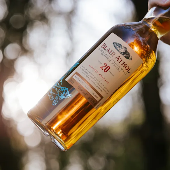 A close-up of a hand holding a bottle of Blair Athol 20-year-old Highland Single Malt Scotch Whisky Limited Release.