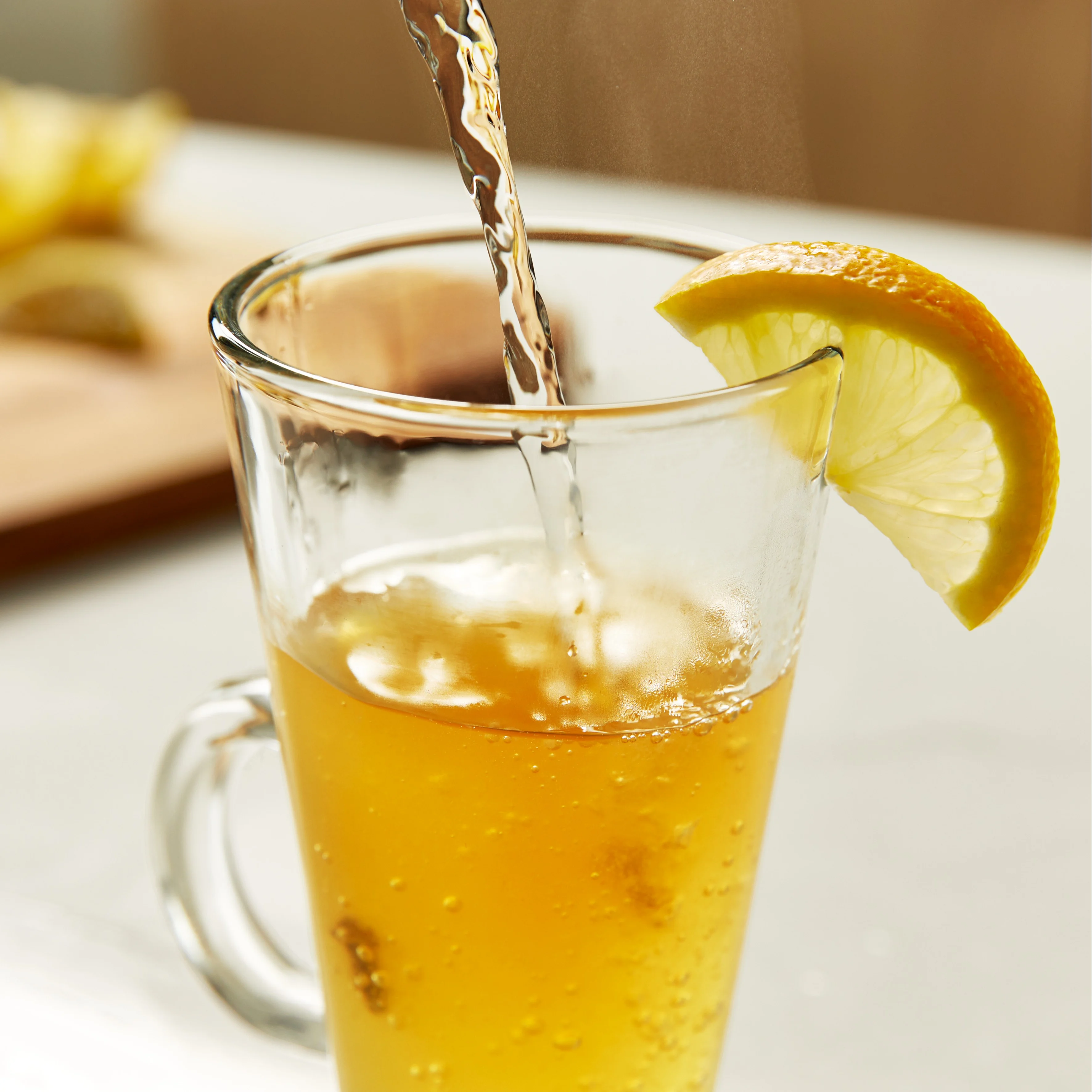 Heißes Wasser wird in ein hitzebeständiges Glas gegossen und mit einer Zitrone garniert