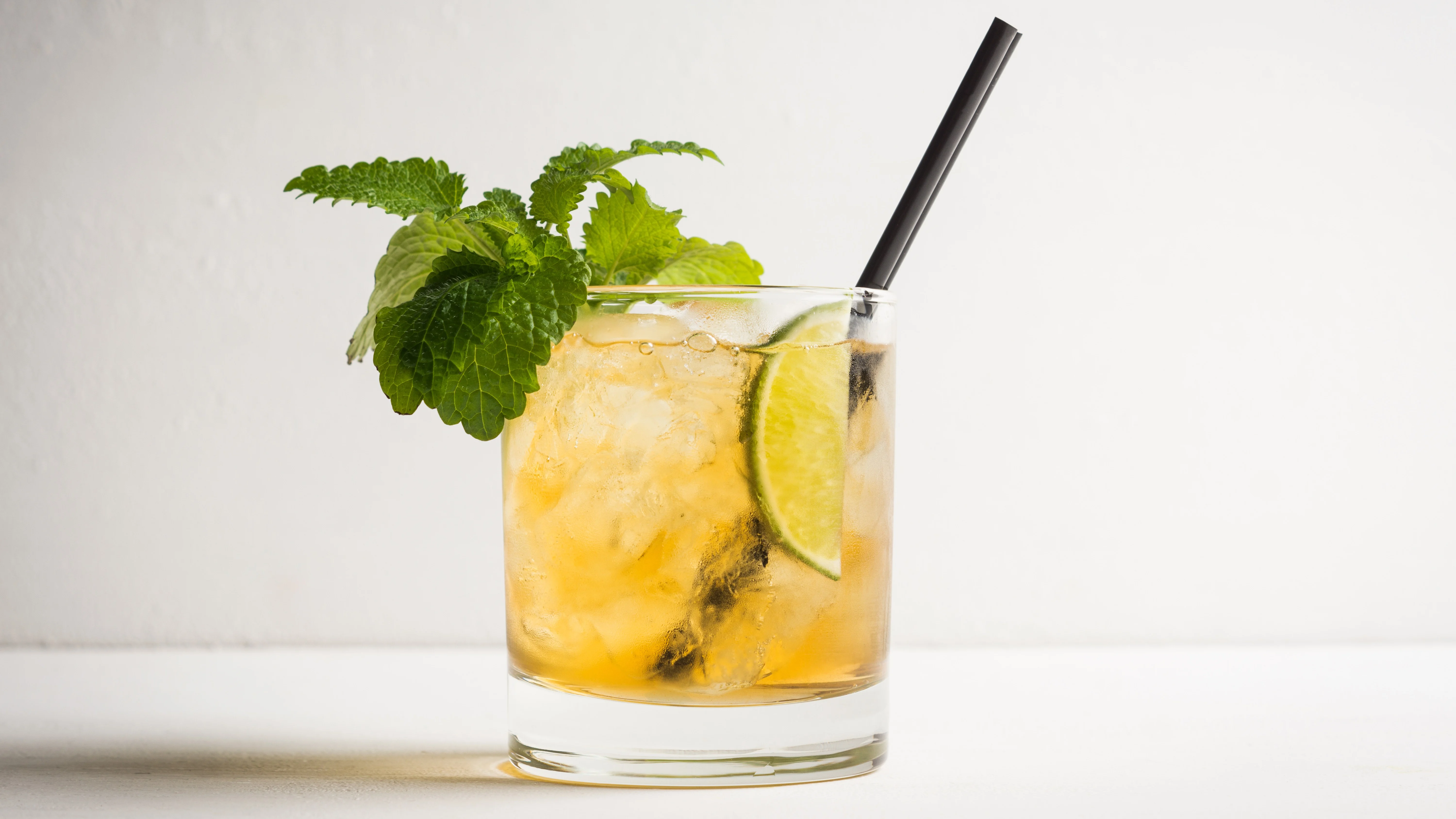  A Whiskey Smash cocktail in a rocks glass with a mint sprig garnish and a citrus segment