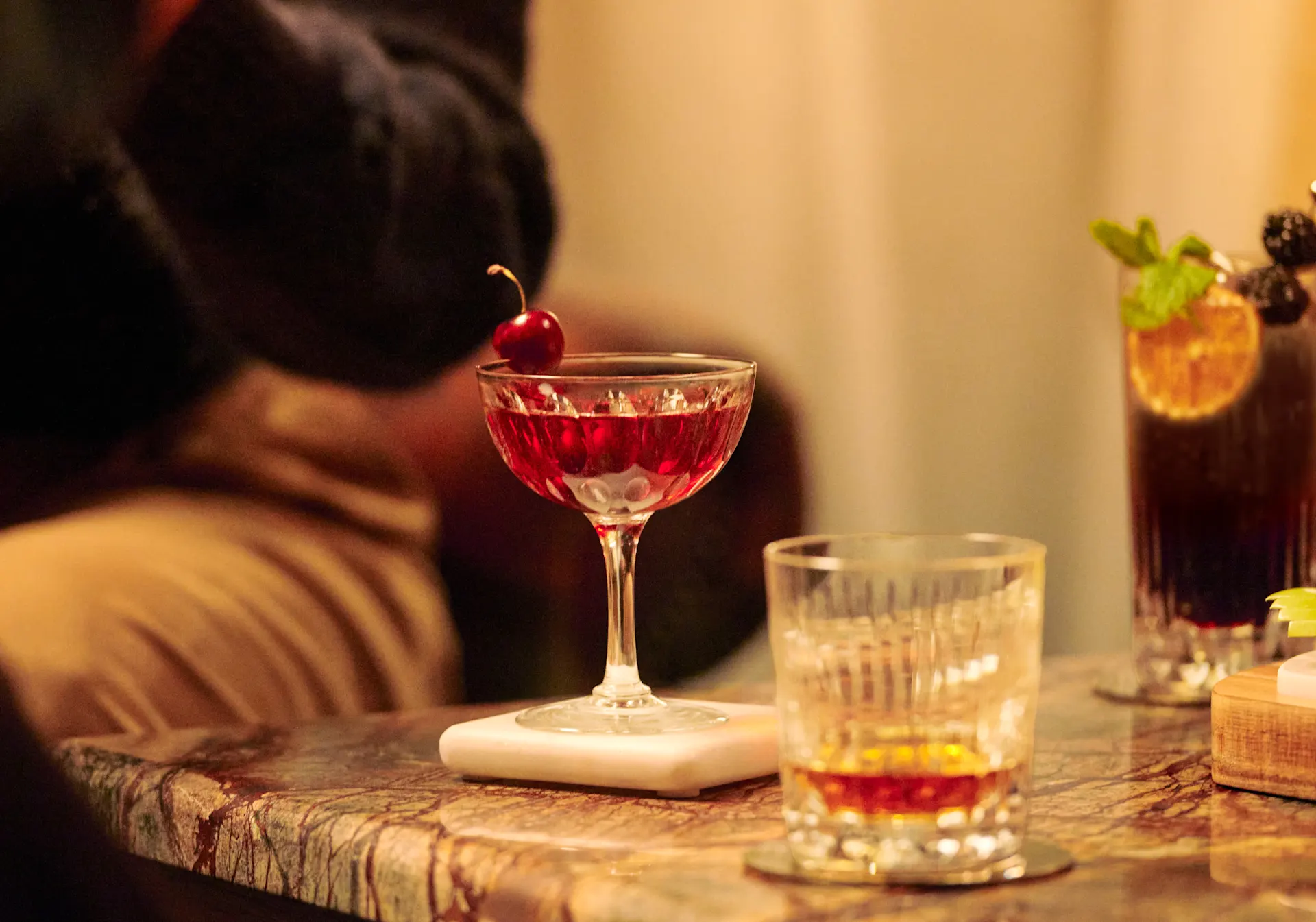 A whisky cocktail in a coupe and a whisky drink in a rocks glass 