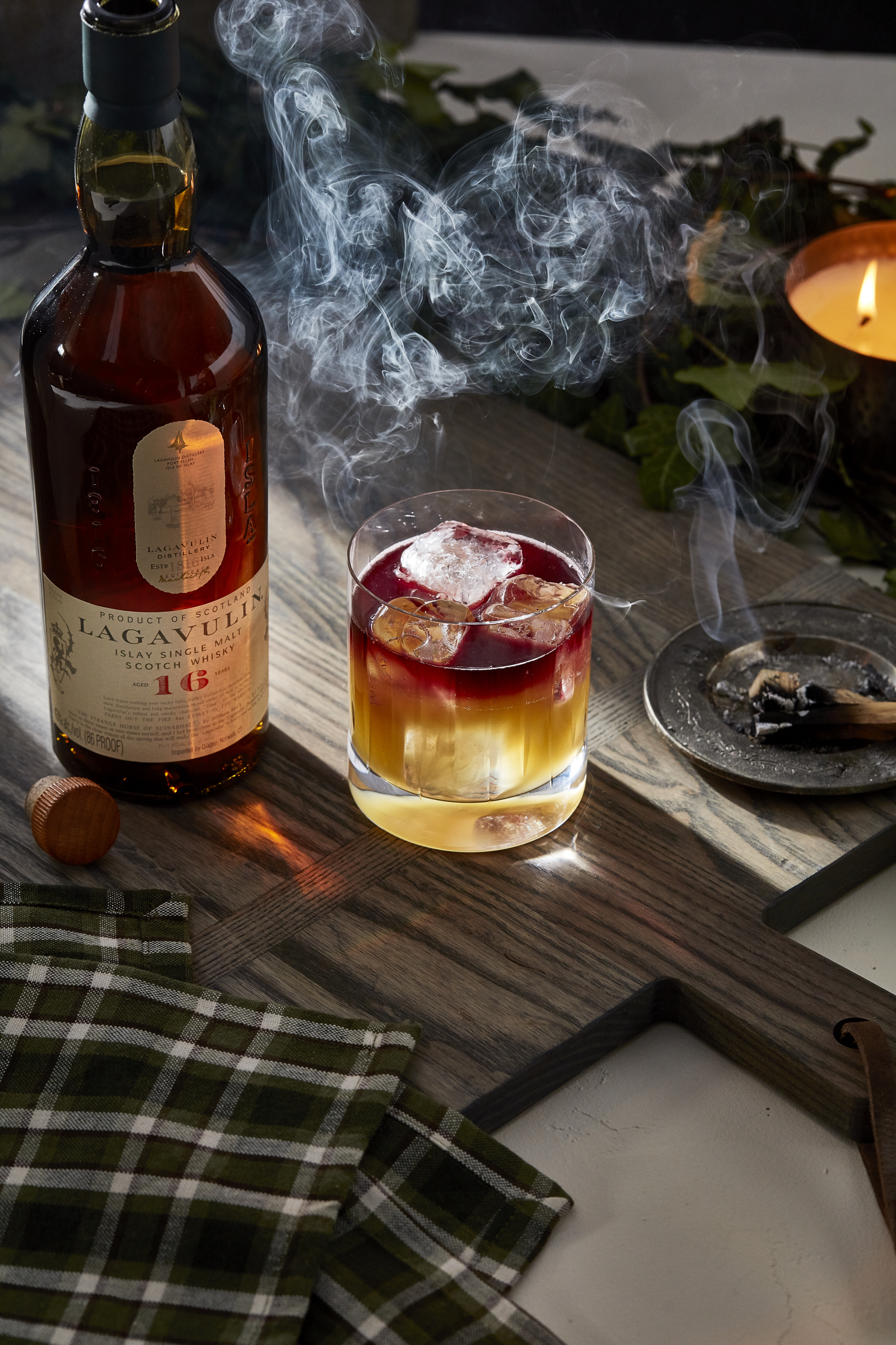 A lowball cocktail sits next to a bottle of Lagavulin 16 year old whisky