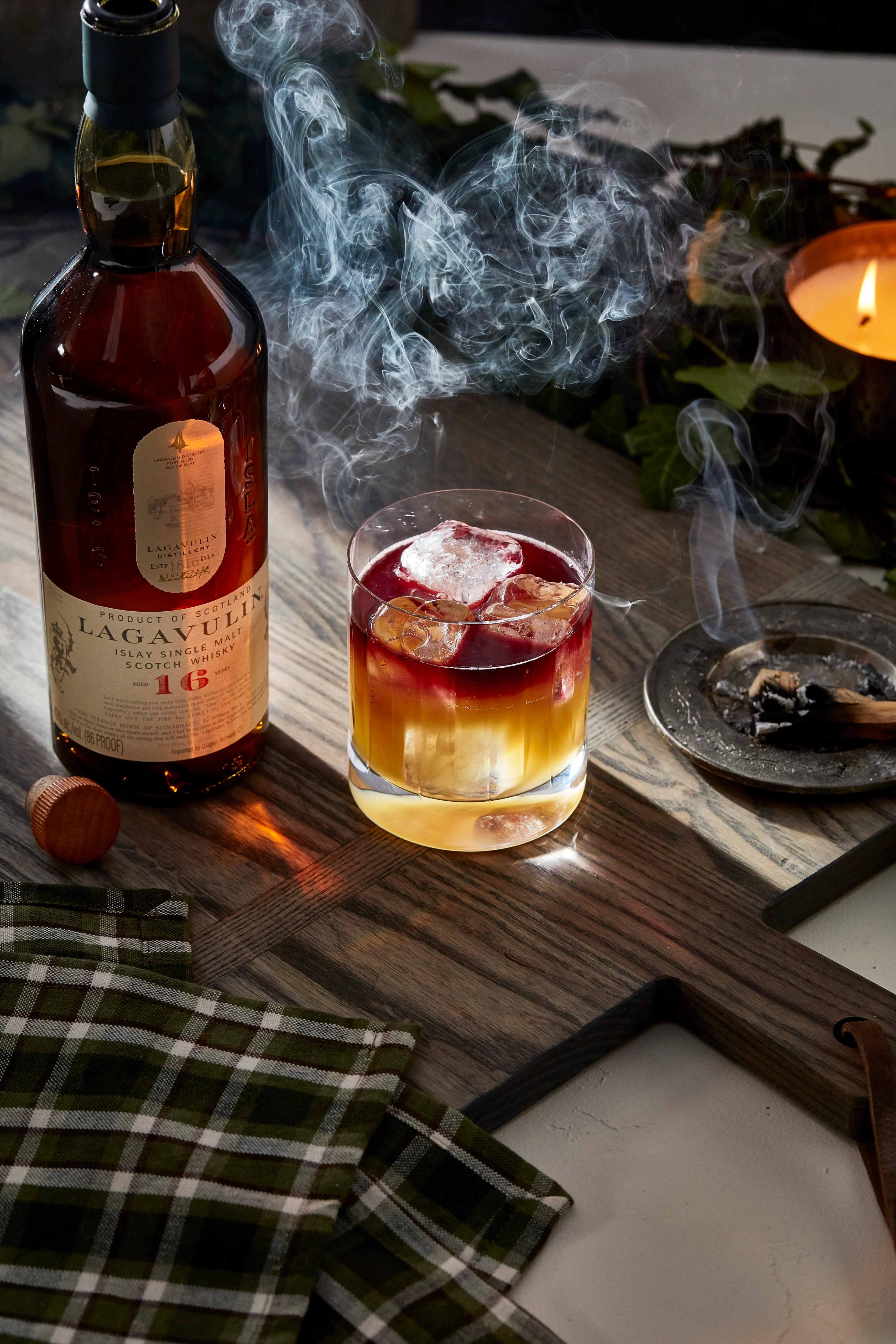 A lowball cocktail sits next to a bottle of Lagavulin 16 year old whisky