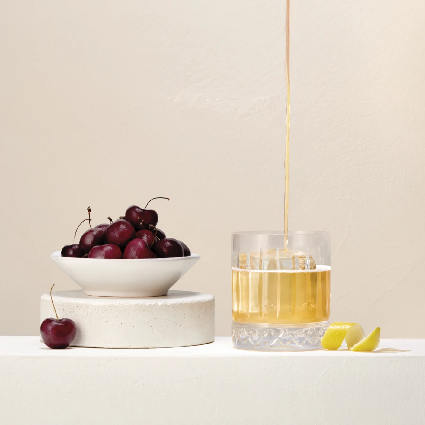 View recipes Whisky being poured into a glass next to a bowl of cherries