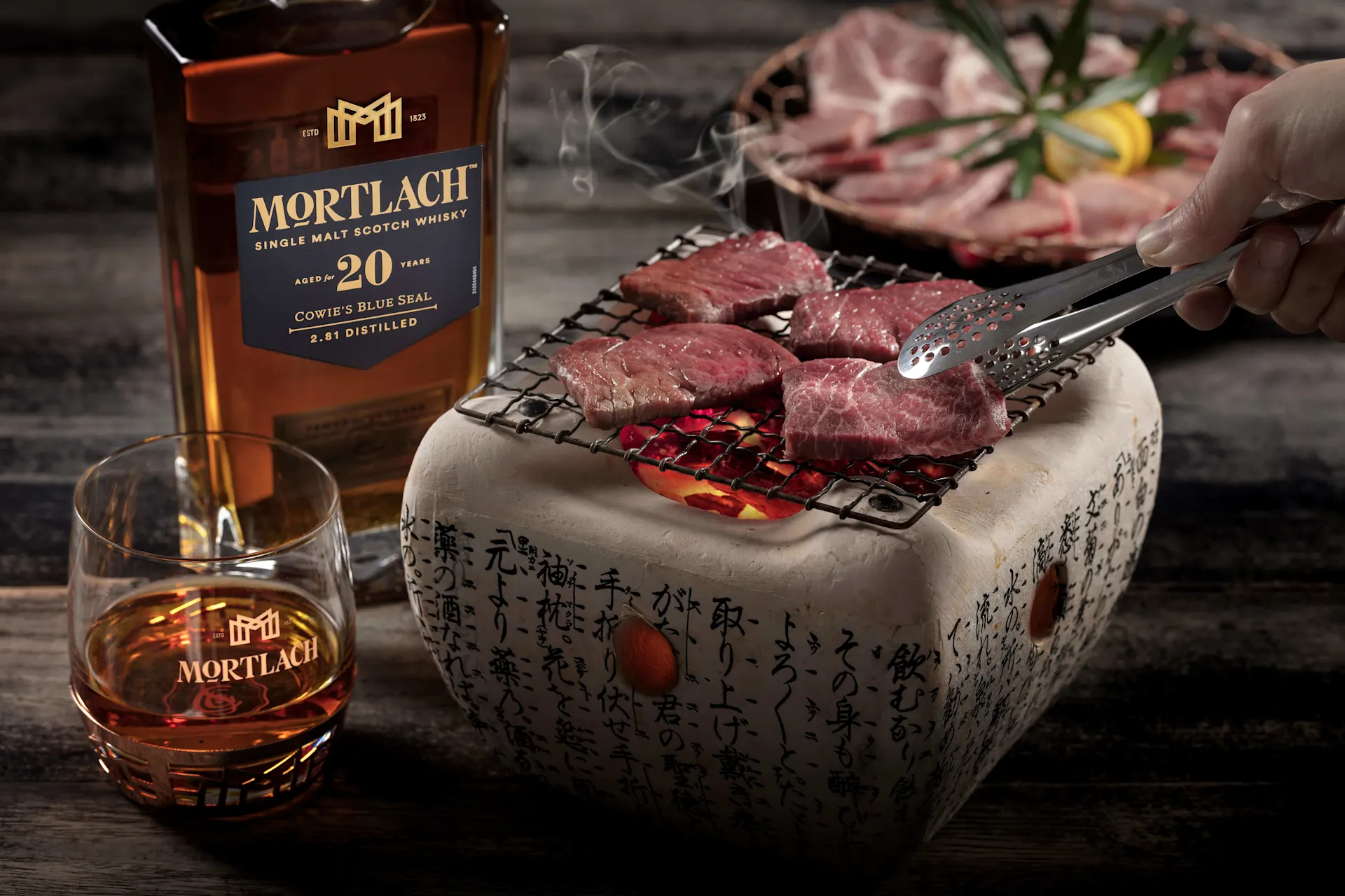 一瓶20年陸克威士忌、一杯威士忌和幾片在火上烤的牛肉。