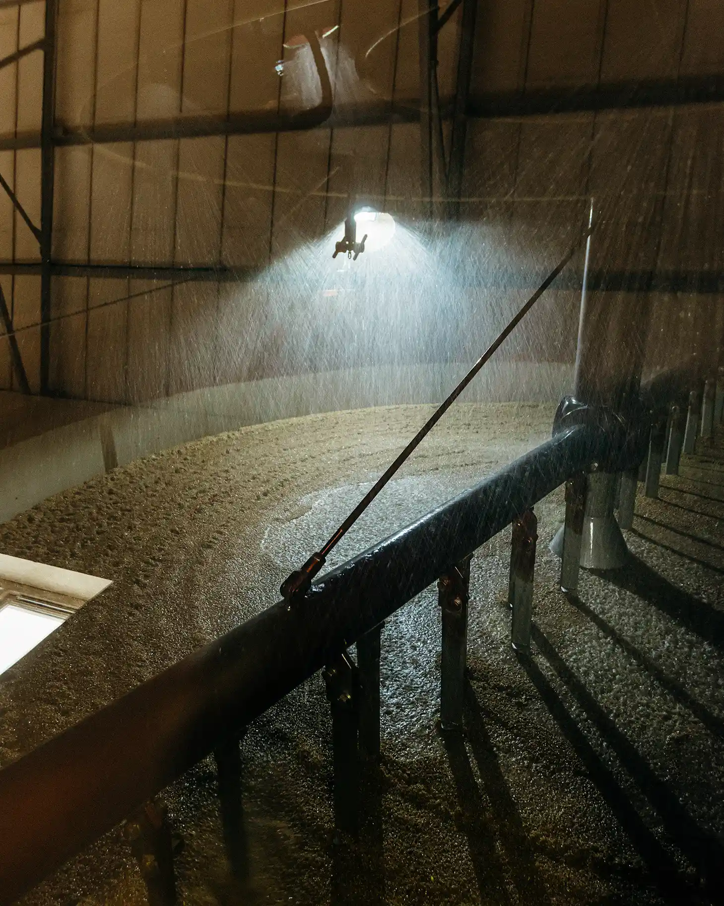 A big barrel of barley is being sprayed with liquid from above.