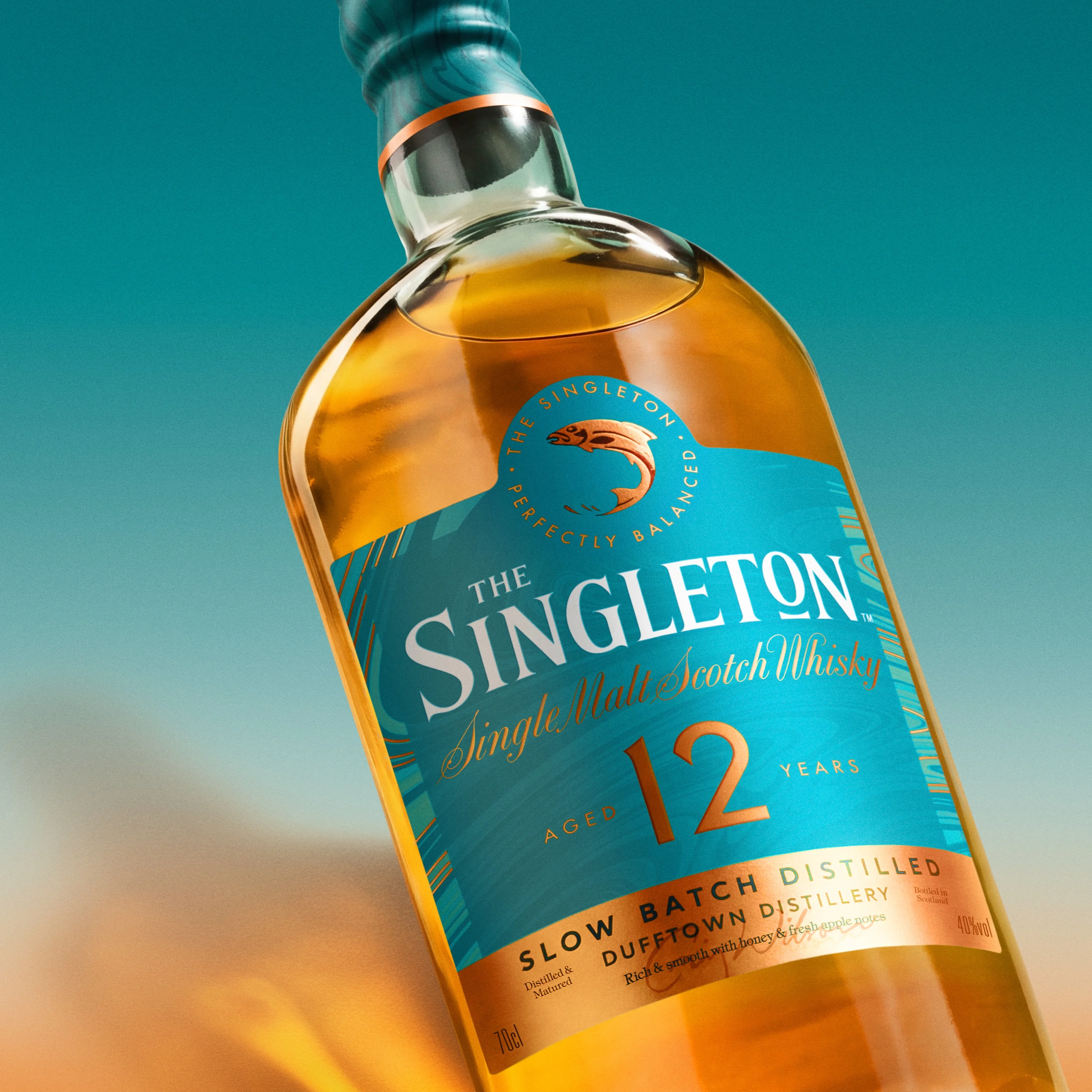 A bottle of The Singleton 12 Year Old Whisky against a blue and yellow sunset